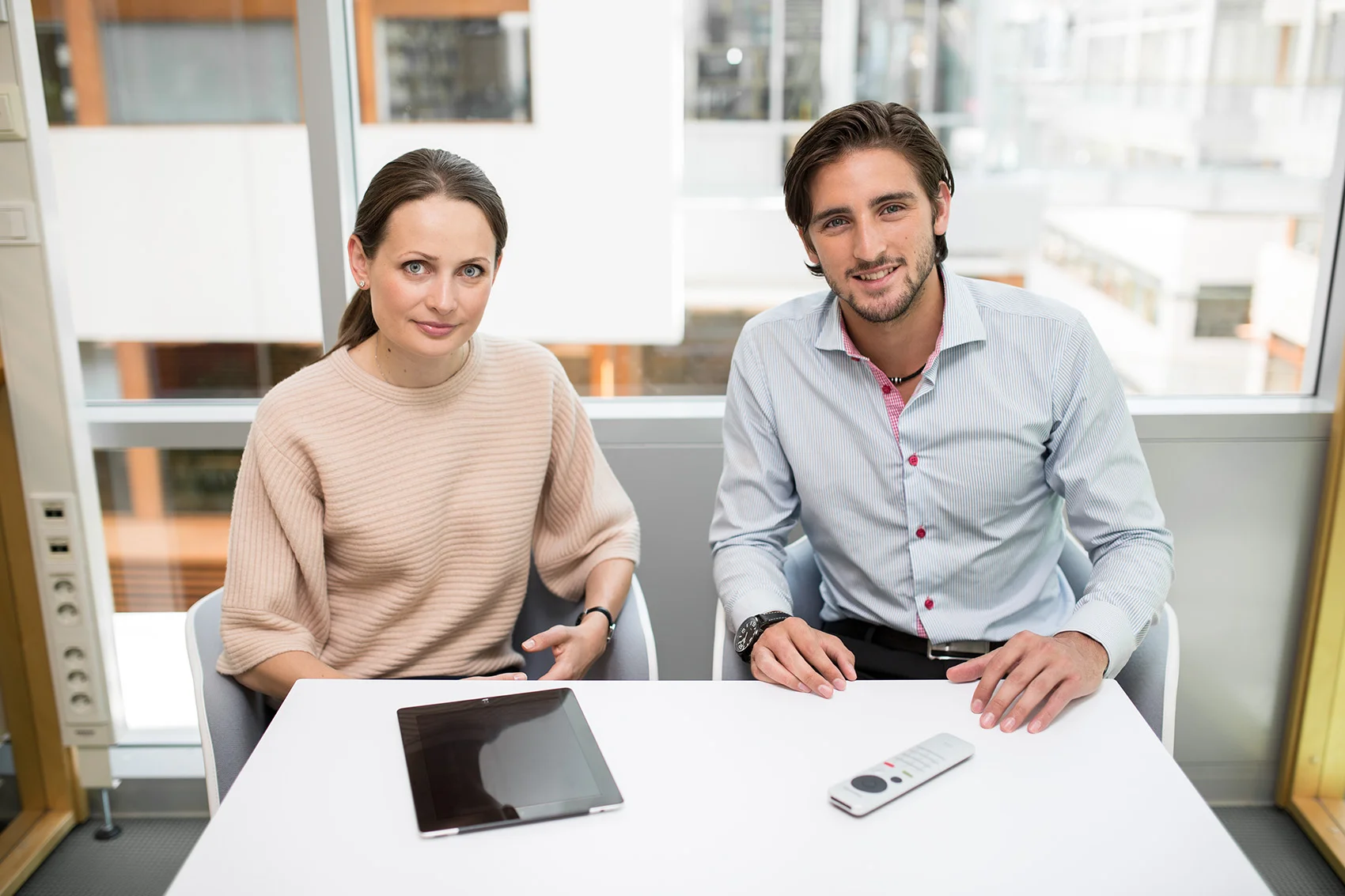 fashionable younger man and woman at work with a remote control and a tablet