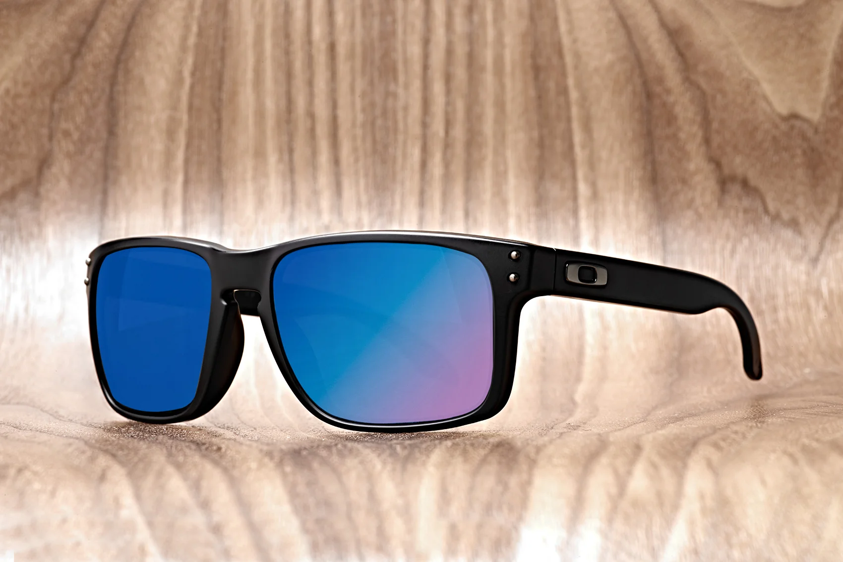 oakley sunglasses with colorful lenses on wood background