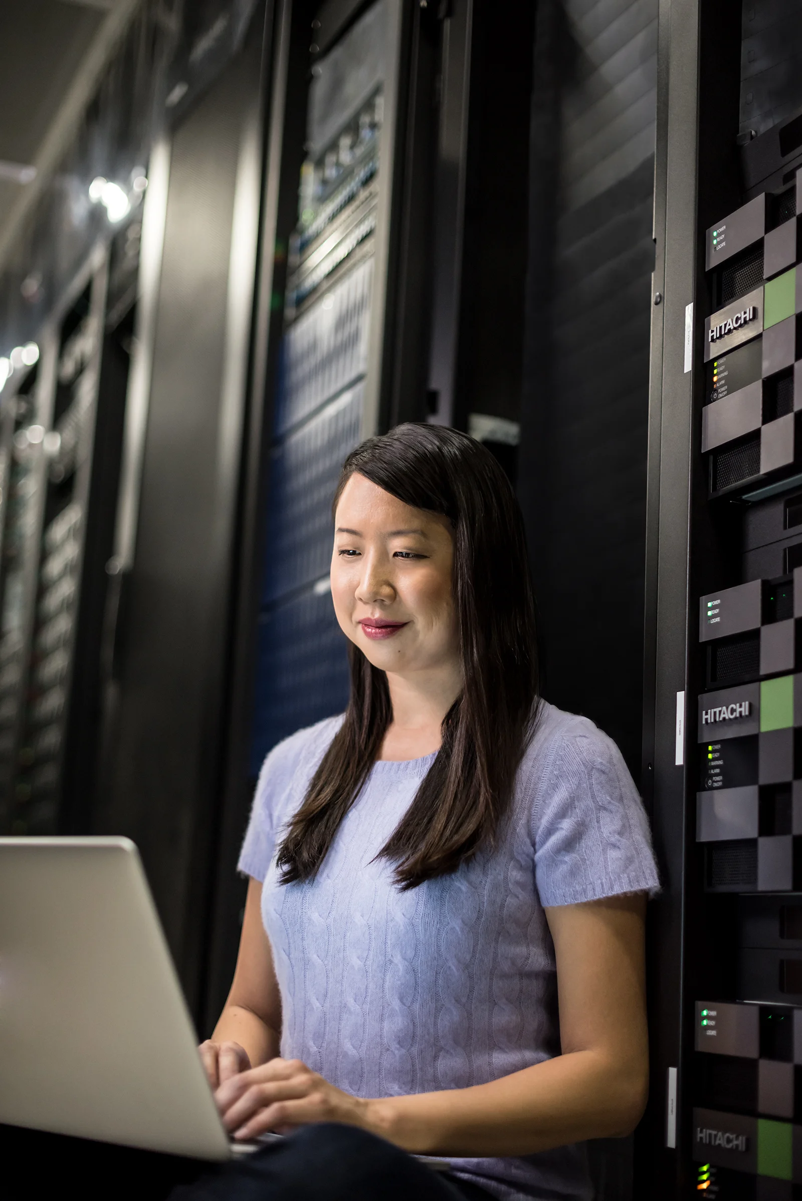 Young asian woman on a laptop in a data center