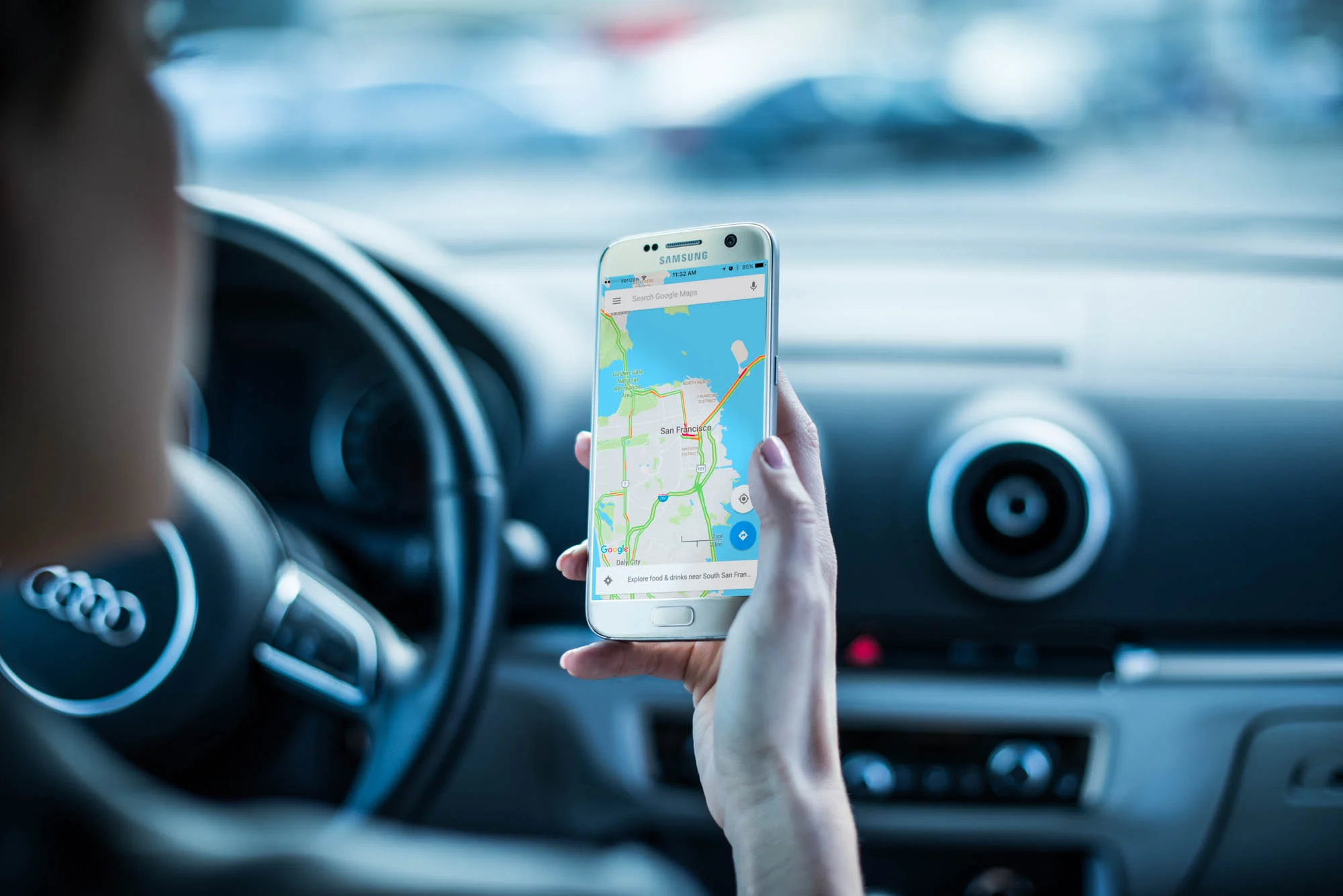 Woman in a Audi car looking at a map on a cellphone