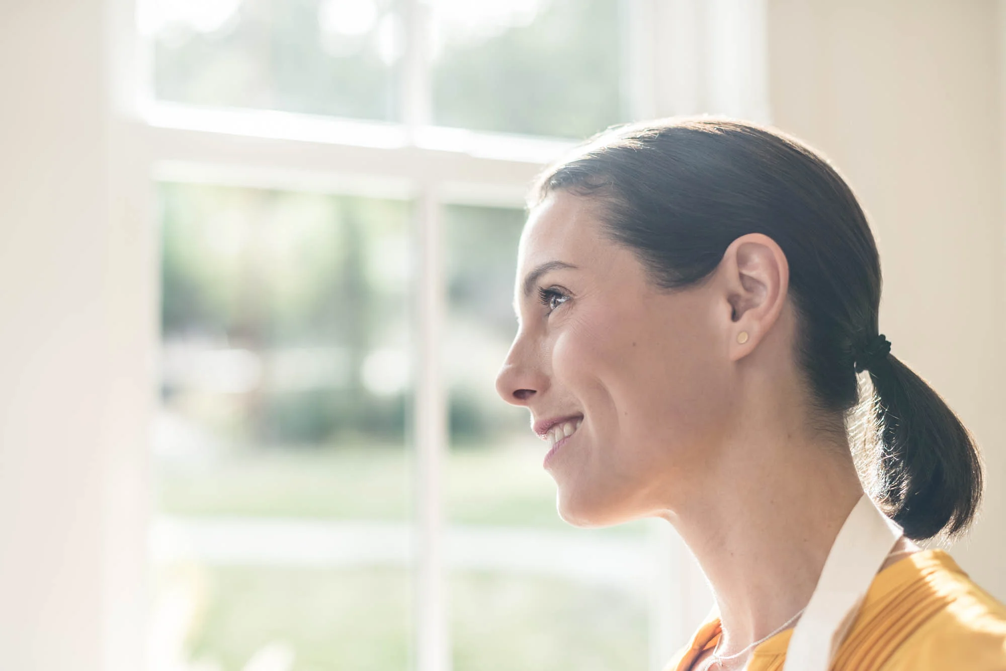 Young woman smiling and looking out of a kitchen window