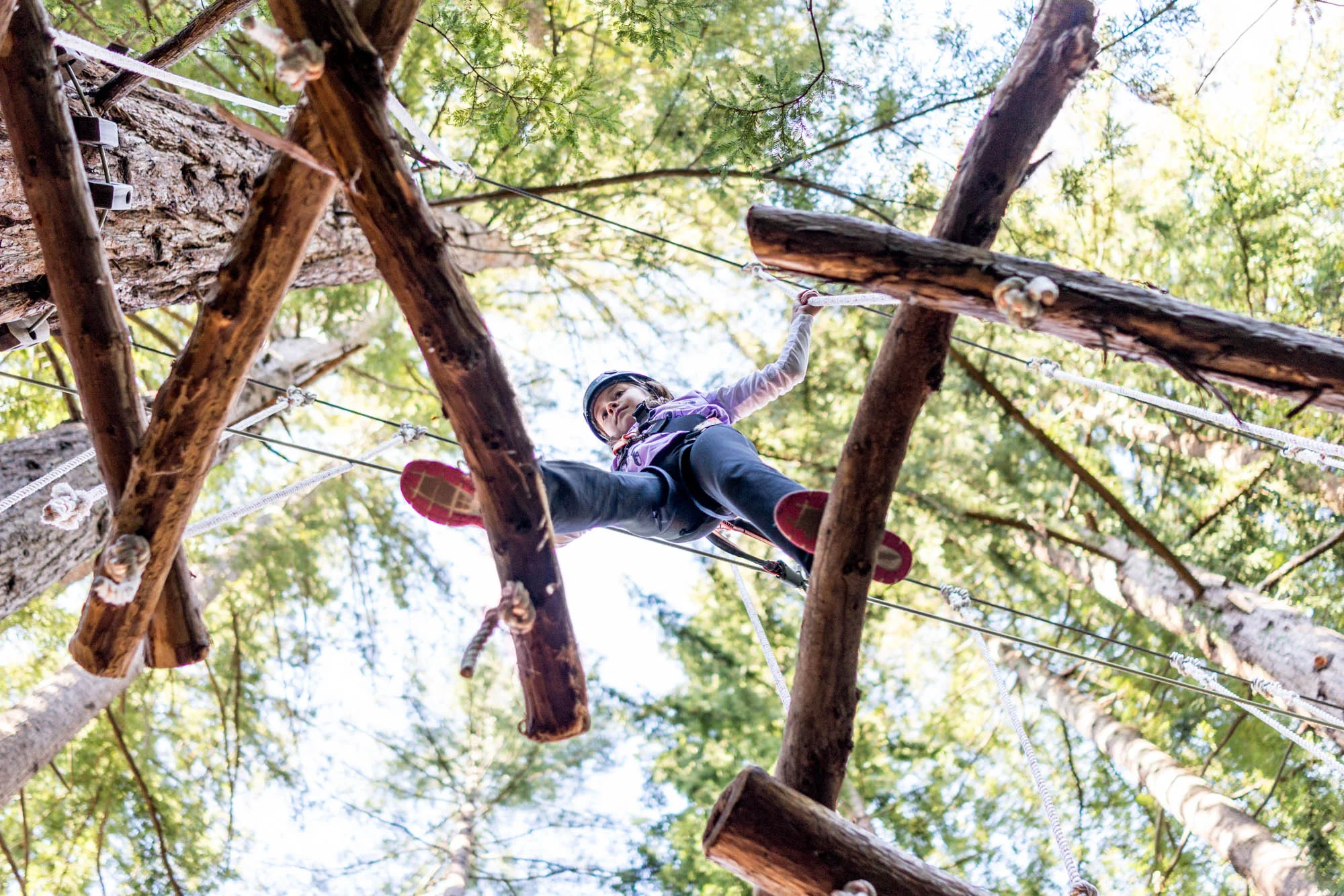 girl walking through a ropes course in the redwoods