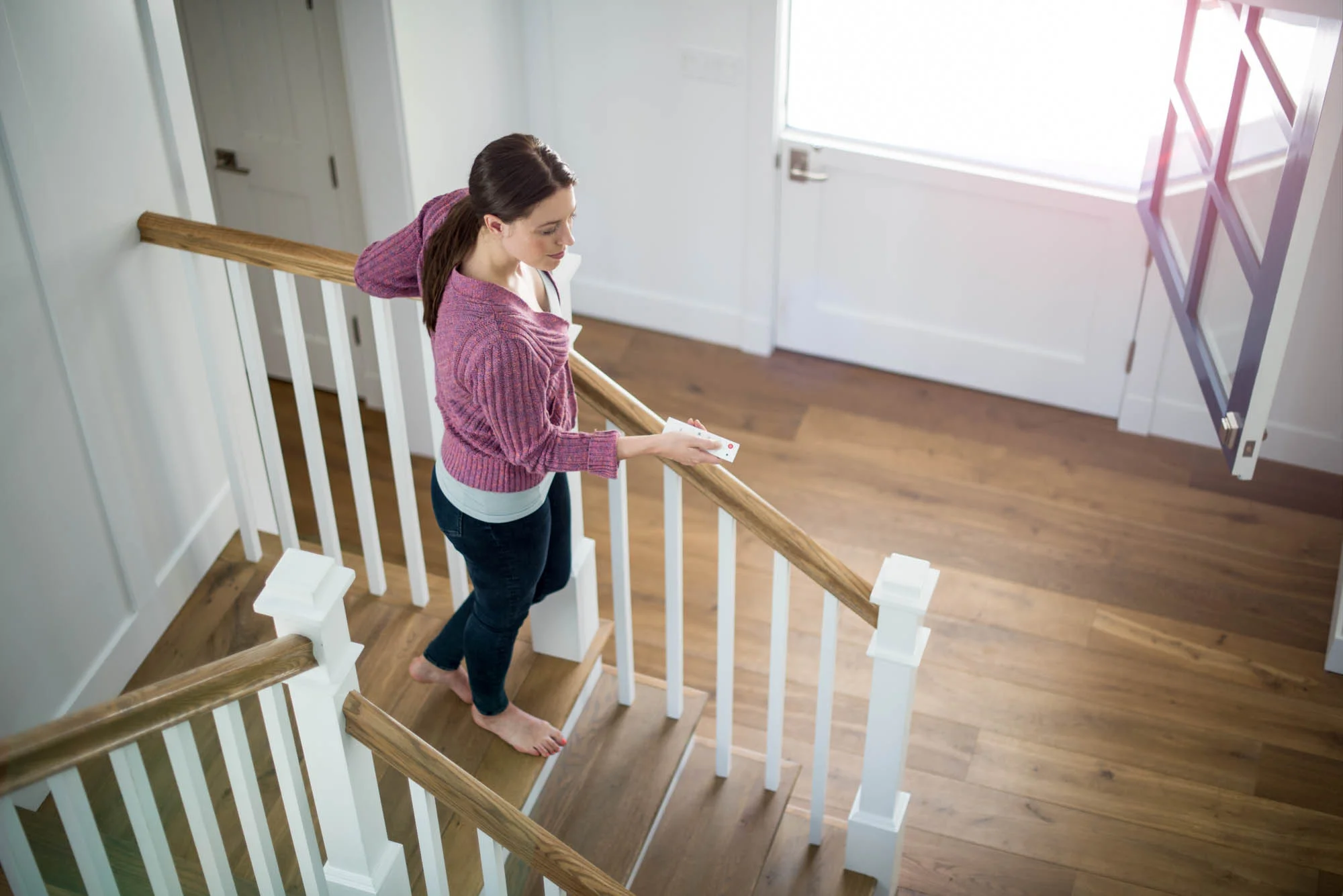 Young woman walking down stairs holding a remote