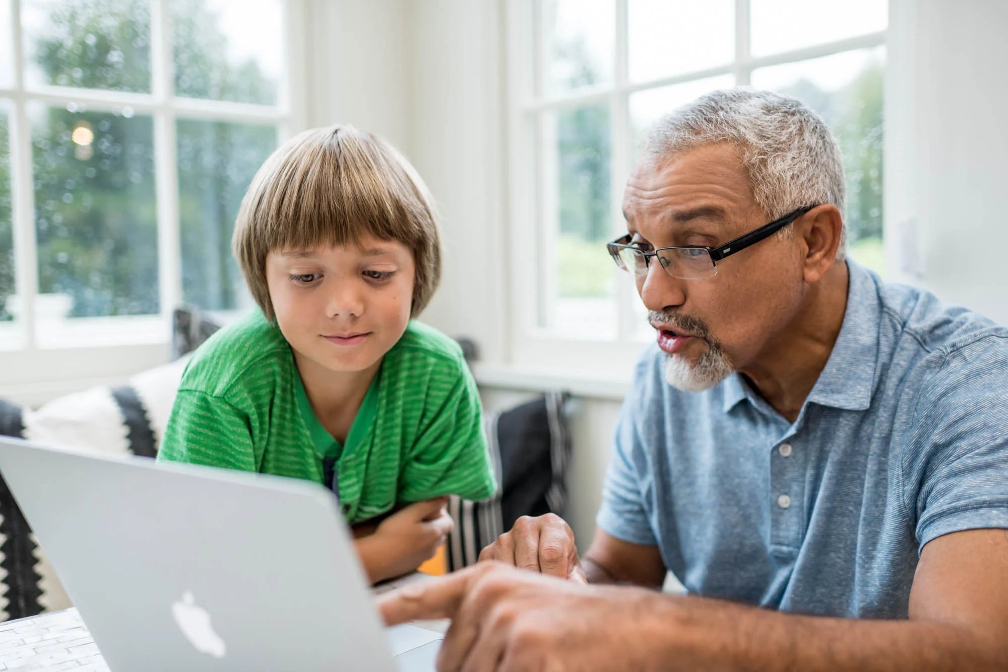 older man looking at a laptop with a young boy
