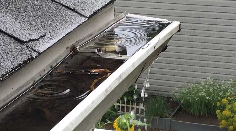  clogged gutter overflowing with rain 