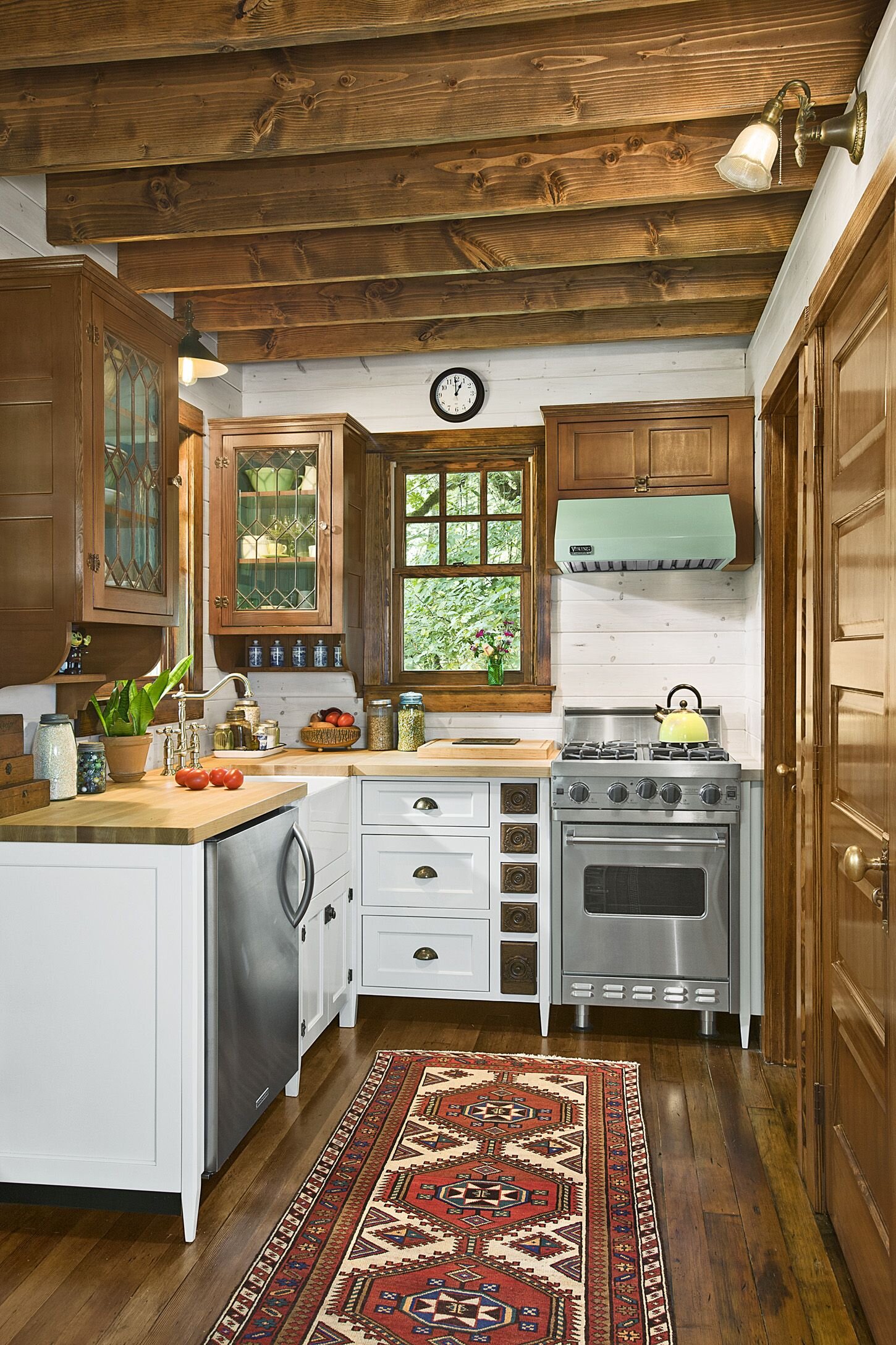  This tiny kitchen has a small oven and an under the counter refrigerator. Instead, they opted for a large farmhouse sink to make cleaning up easy.  