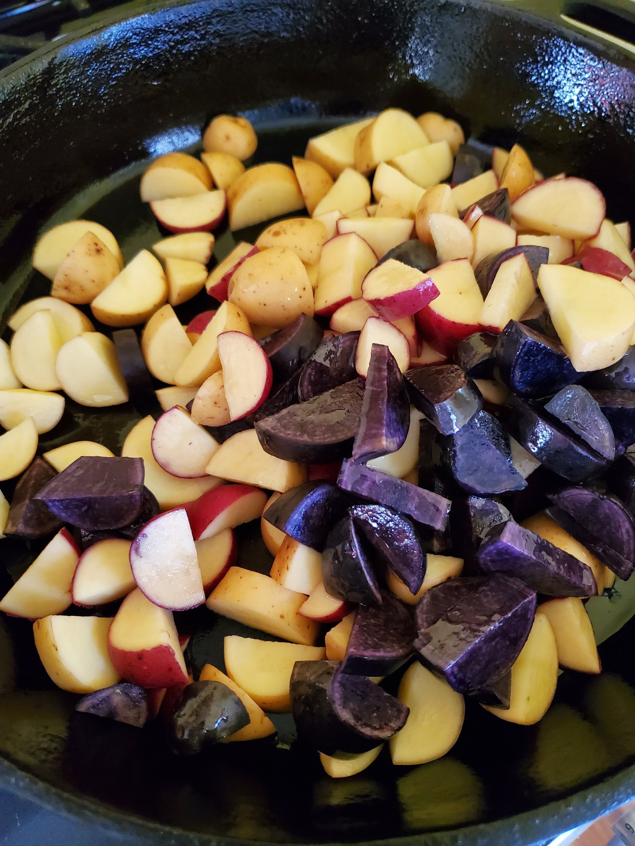 Adding the potatoes to the pan, including those lovely purple ones!