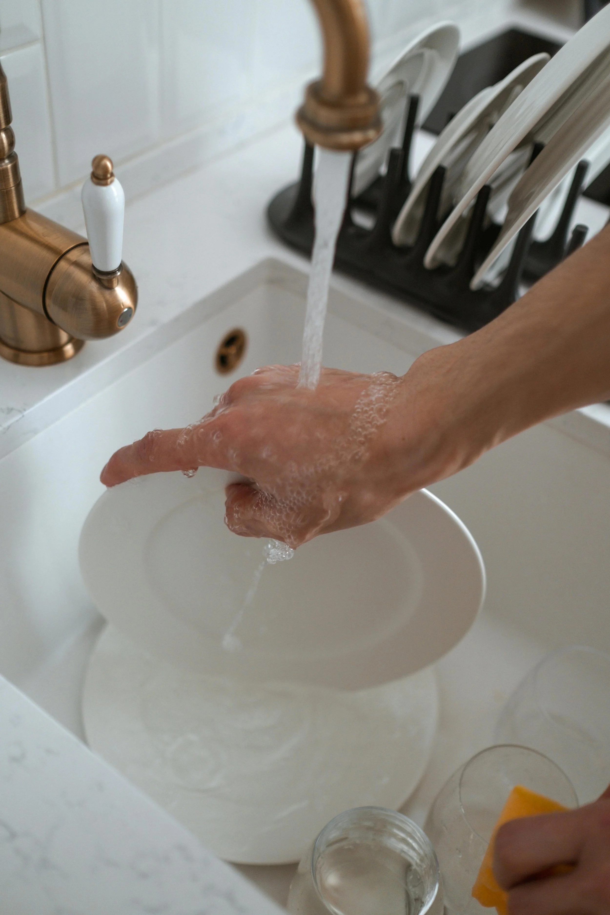 Person handwashing dishes in a kitchen sink