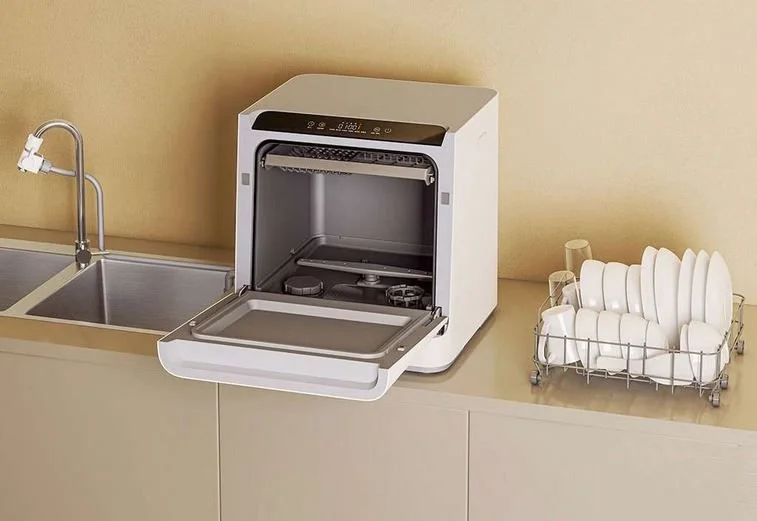  A compact dishwasher on the kitchen counter, along with the rack sitting off to the right.  