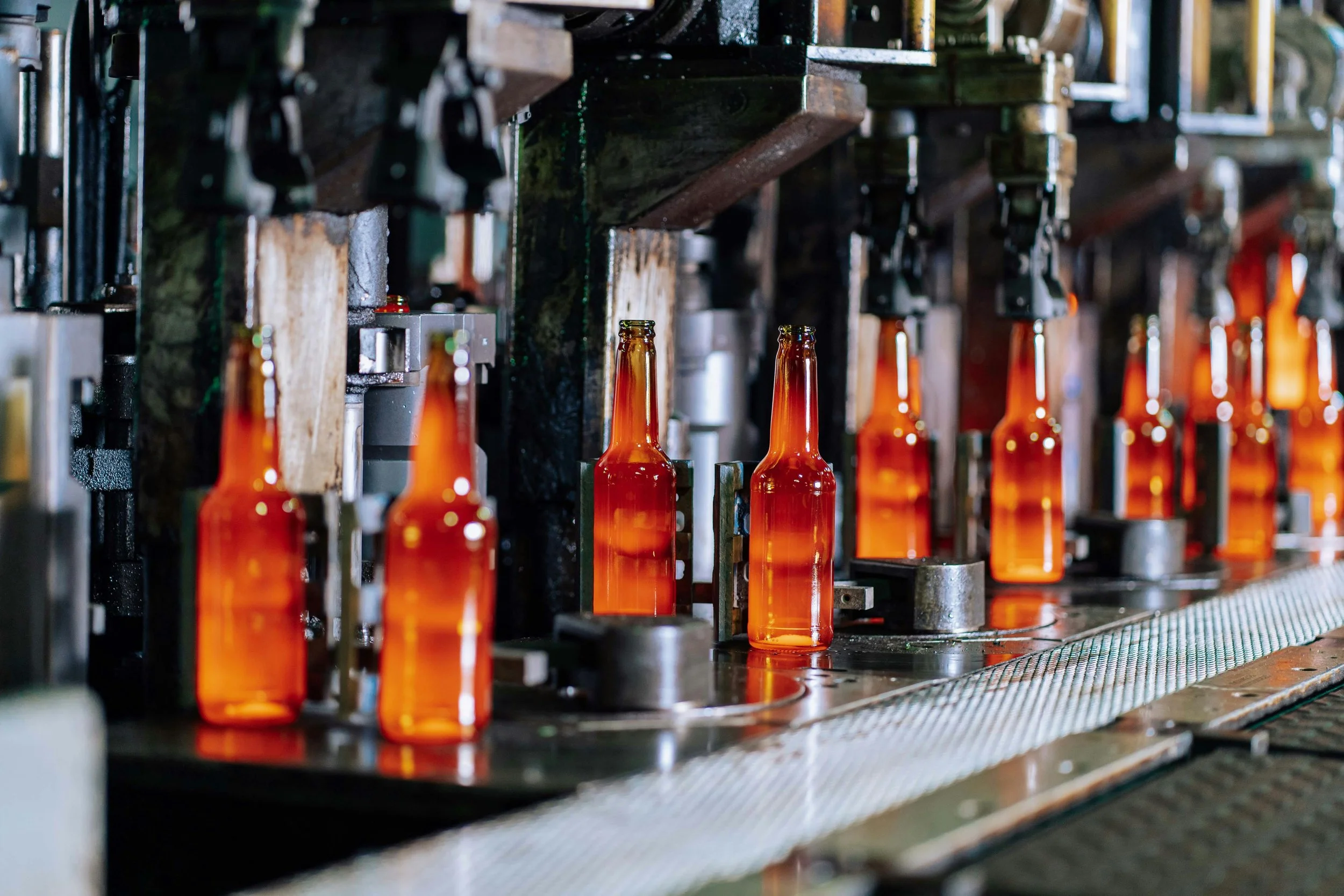 Glass bottles moving along a factory production line, representing early industrial manufacturing before modern consumer safety regulations