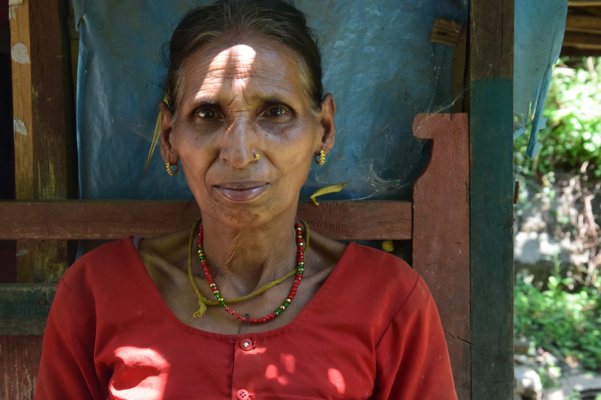 KHOLAPARI KANCHI DIDI, age 58 She never went to school. She doesn't know how to read and write. She was born and raised in the Himalayas and taught at the age of 7 how to plant rice and grow vegetables, how to take care of the animals. But her everyday task was to take care of her younger brothers and sisters, cooking meals for them and collecting wood for fire from the forest. Her marriage was arranged when she was 11 years old. Her husband was 13 at the time. She has two children; she gave birth to a son at the age of 17 and to her daughter 12 years later. Her husband left and married another woman. She moved back to her village and remains there alone. Her children stayed with their father, and she was able to visit them whenever she wanted. She enjoys smoking cigarettes and listening to Nepalese folk music. She lost her house during the earthquake, but never lost her sense of humor. She remains positive, happy. and smiling.