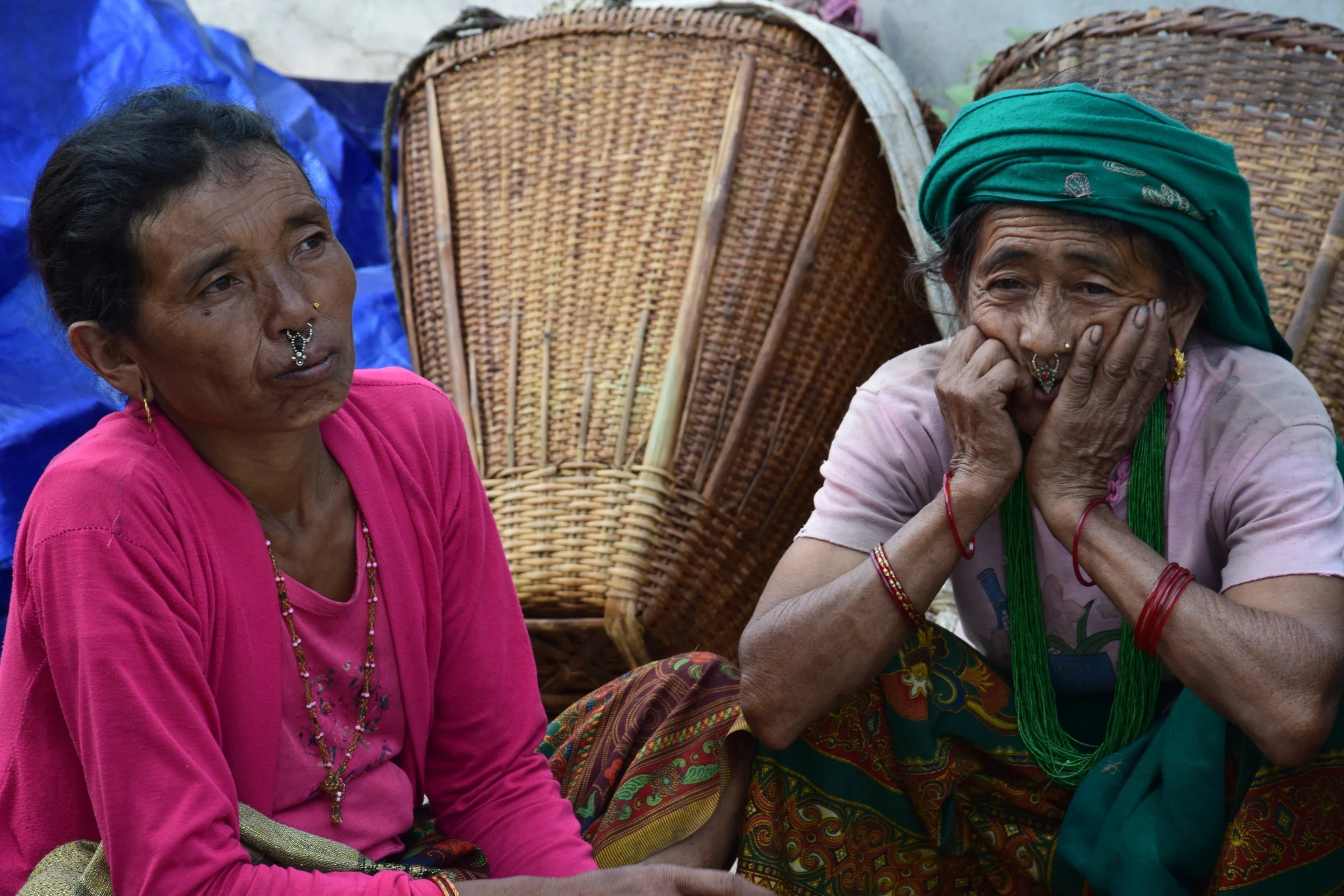 BARAM AND GURUNG DIDI They come from Thumi, a village set very high in the mountains. They are from same village and are best friends always looking out for each other. Their village was completely destroyed during the earthquake by a landslide. About 700 people became homeless that day and they formed a camp to live in at a nearby forest. There was very limited access to water (the landslide had destroyed the village’s water source); the nearest access was one-and-a-half hour walk away (one way). Both Didis come from the family of stone workers who made handmade roofs. They learned this work from their fathers at seven and eight years old and continue teaching younger generations.. They never went to school. They are able to construct houses from stones. I met them during the earthquake and they said that they will be able to rebuild their house. They were sad that since the landslide made the path impassible and they weren't able to get back to what is left of their homes to look for their belongings. All their food storage (rice, lentils, corn) was covered by the landslide. The whole village was left with nothing to eat. We were able to organize aid for their village.