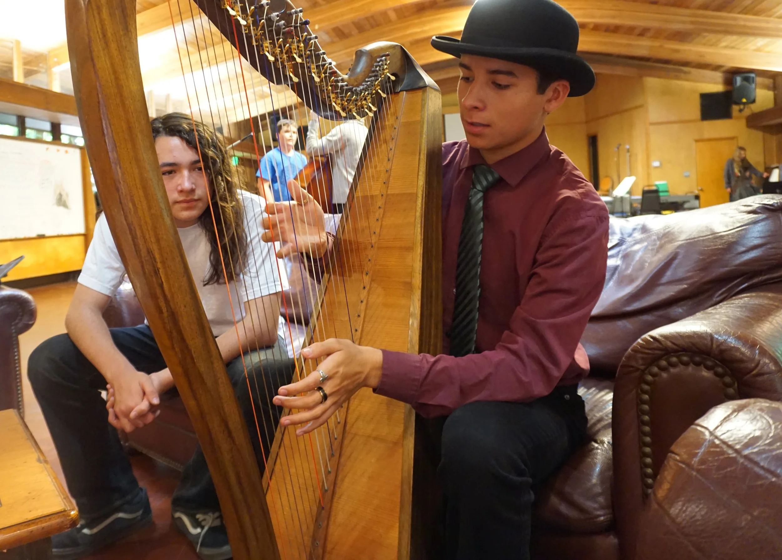 A teenager tries out a Celtic harp while another looks on