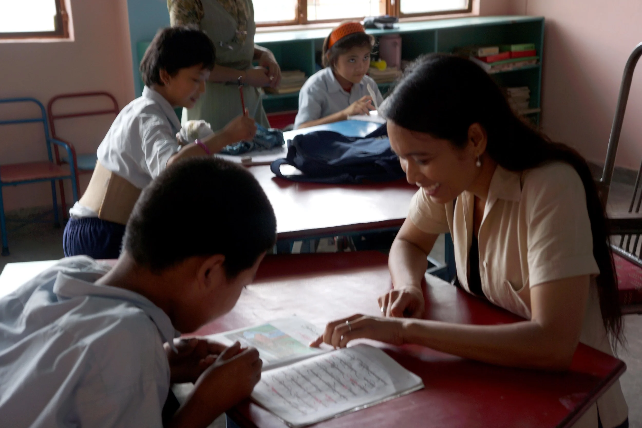 Ana Rowena McCullough sits across from a Tibetan boy, mentoring him