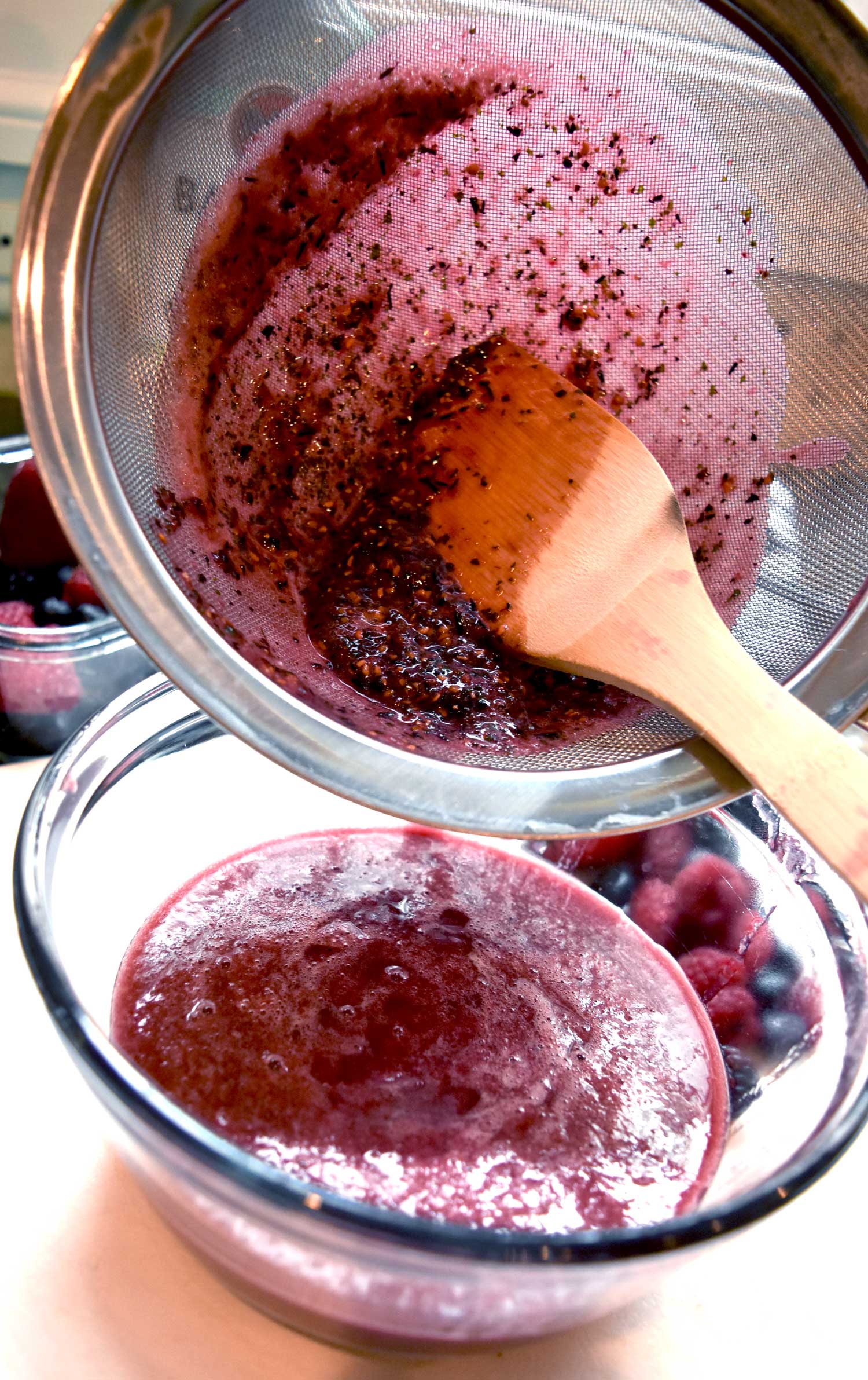 Scrape the seeds away and press with the back of a spoon or spatula to more quickly filter out the seeds.