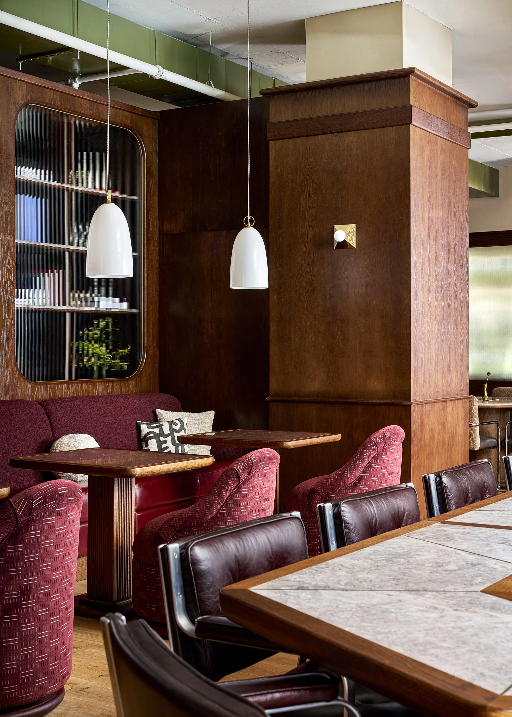 Cozy cafe seating at The Malin DC with burgundy velvet booth seating, wood paneling, and pendant lighting.