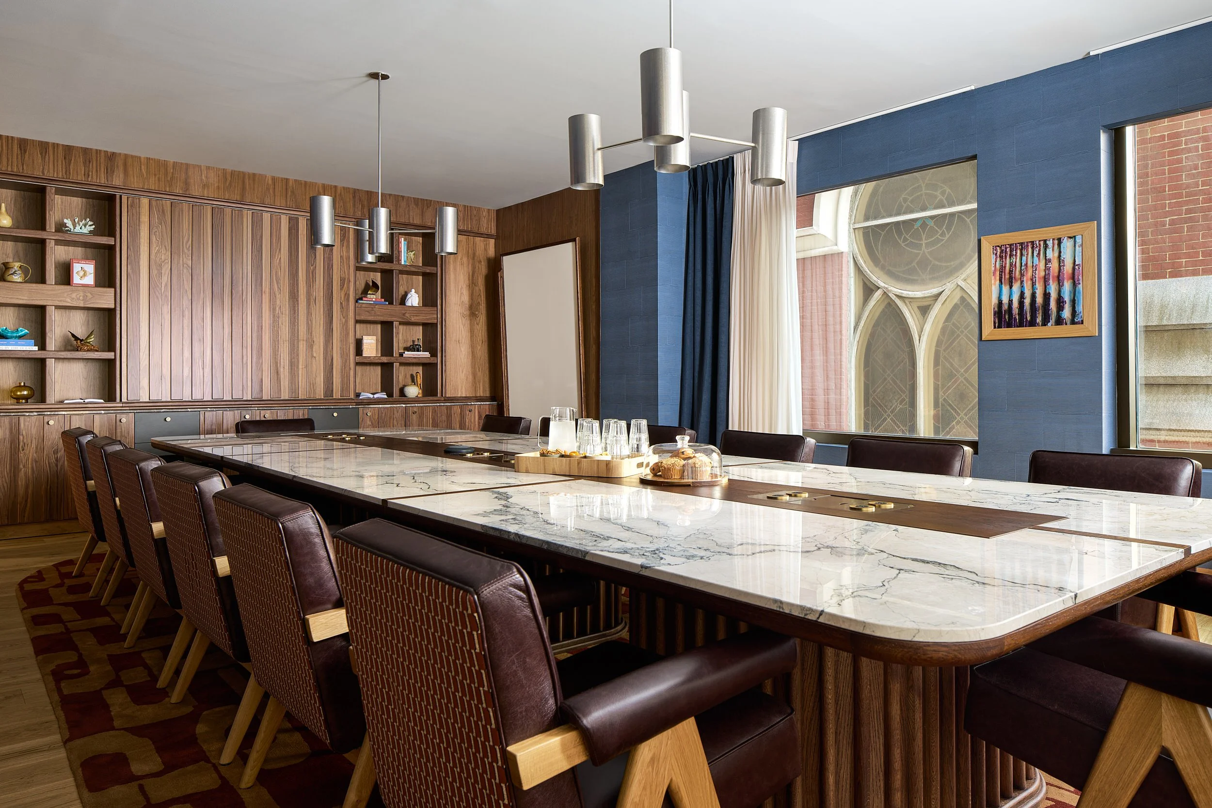 Large conference room at The Malin DC with a marble table, leather chairs, and a blue accent wall framing an arched window.