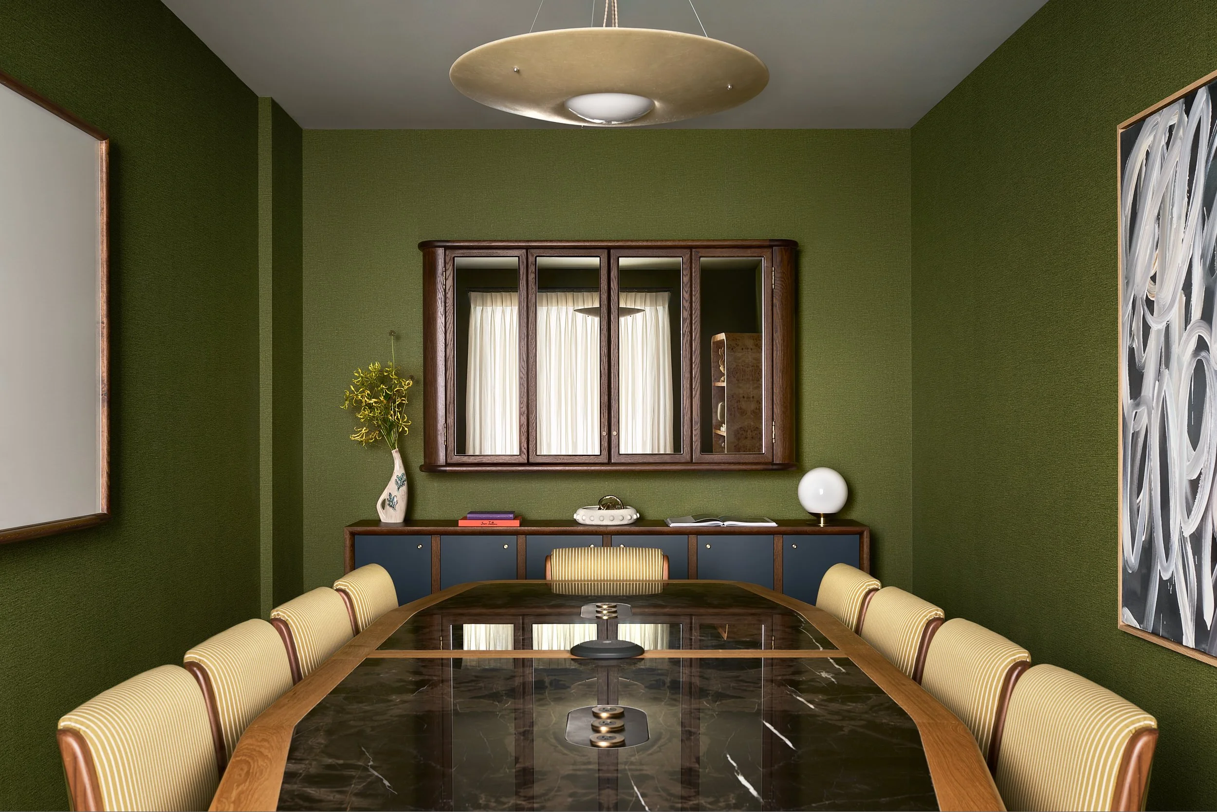 Private conference space at The Malin DC with deep green walls, a marble conference table, and a mirrored cabinet closed.