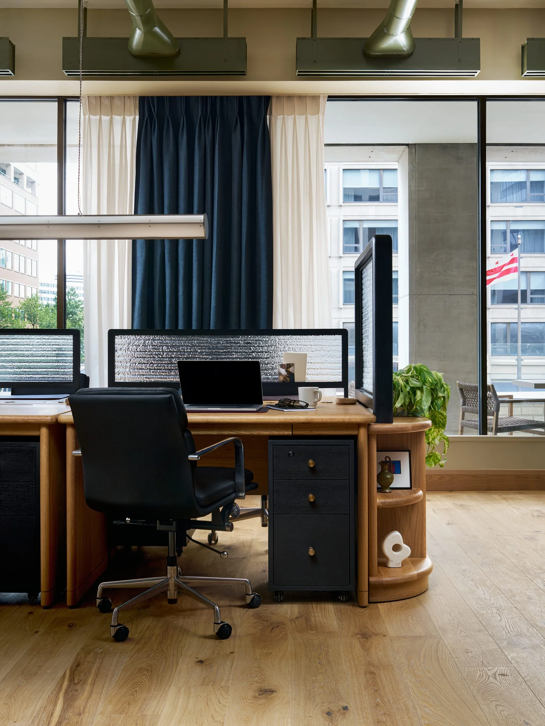 Office workstation at The Malin DC with a fluted glass privacy screen and a window view of the Washington, D.C. flag.