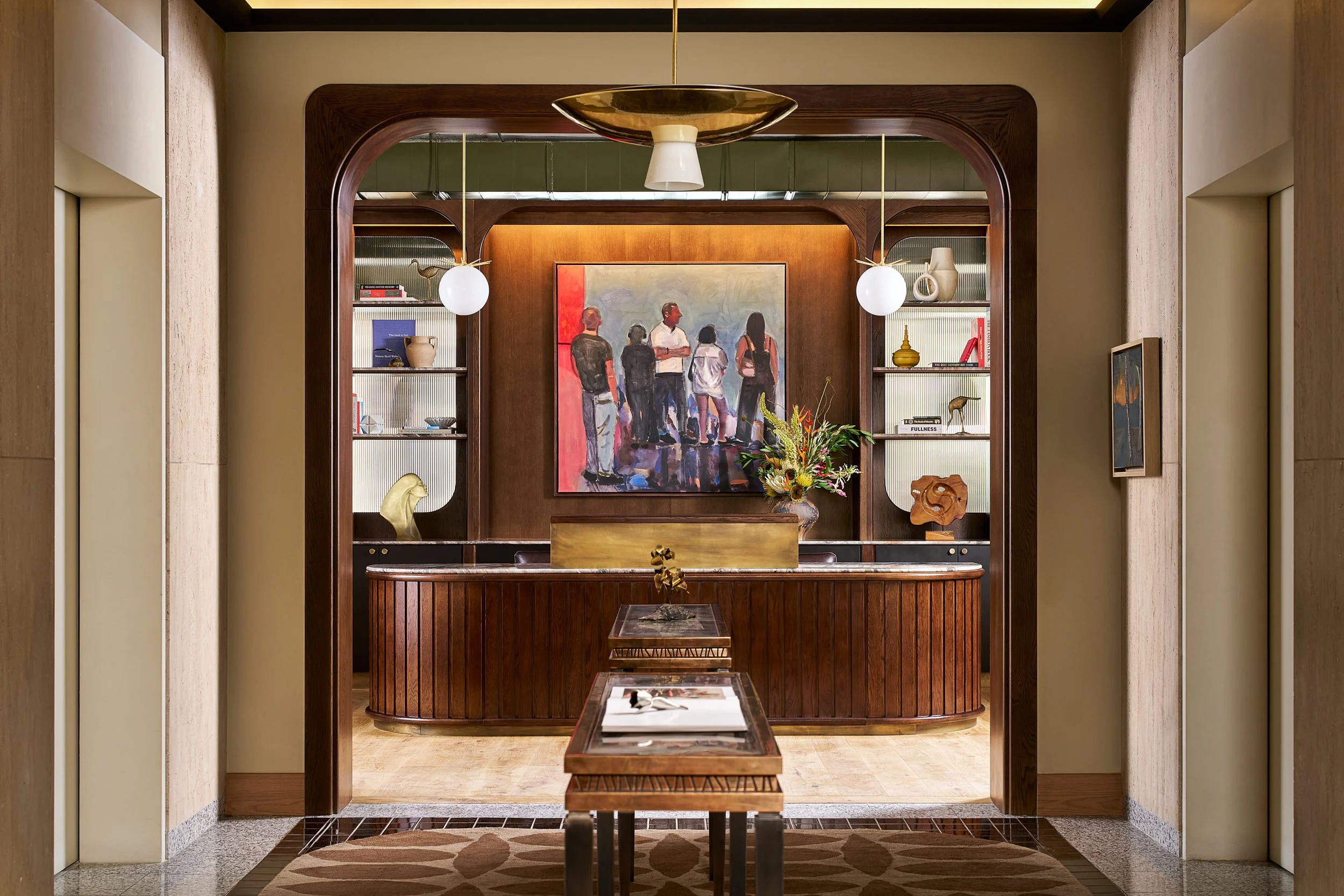 Reception area at The Malin DC coworking space, framed by an arched wood entryway with built-in bookshelves and a figurative painting.