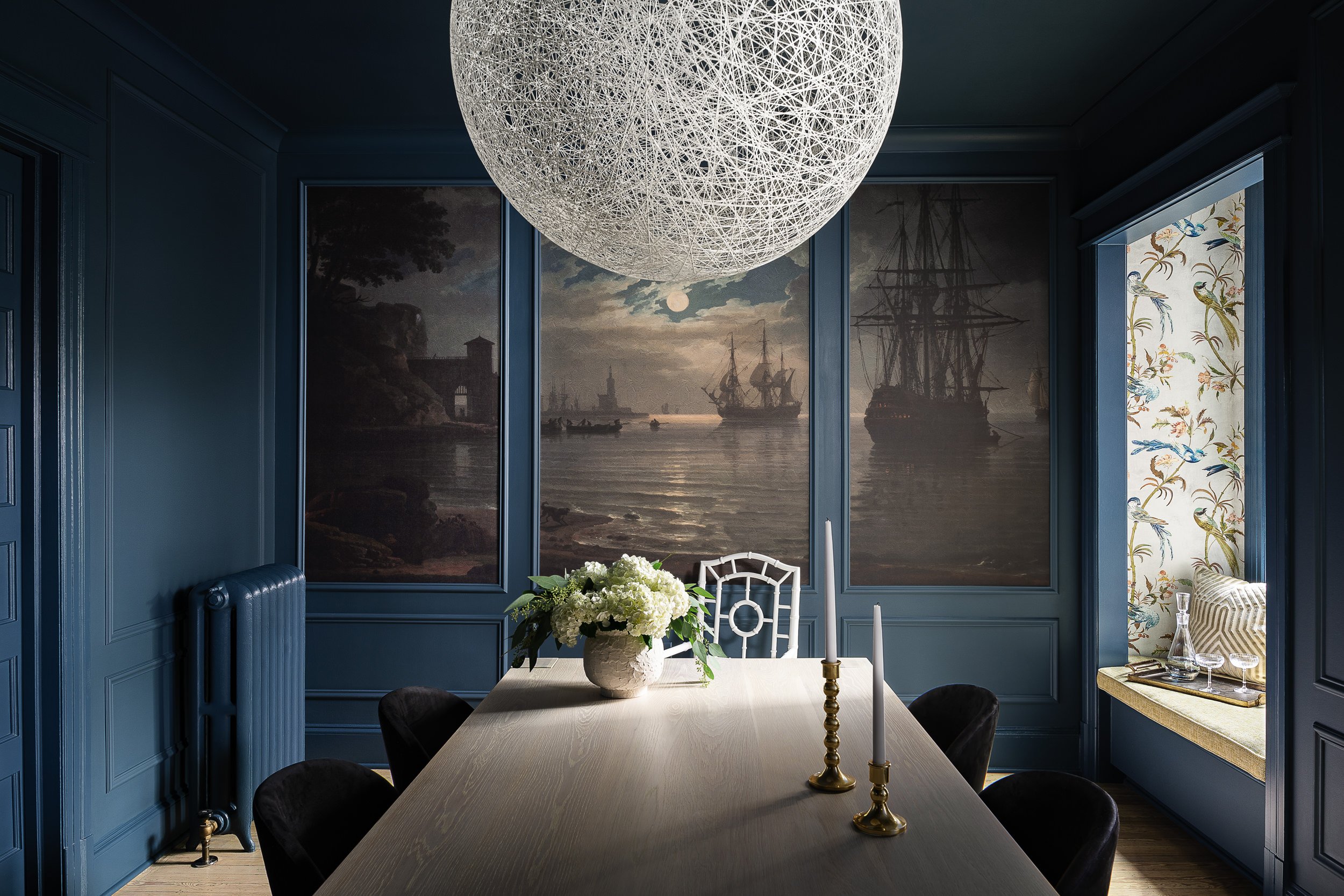 Dining room with dark blue walls and framed ship paintings, interior design photography in Northern Virginia