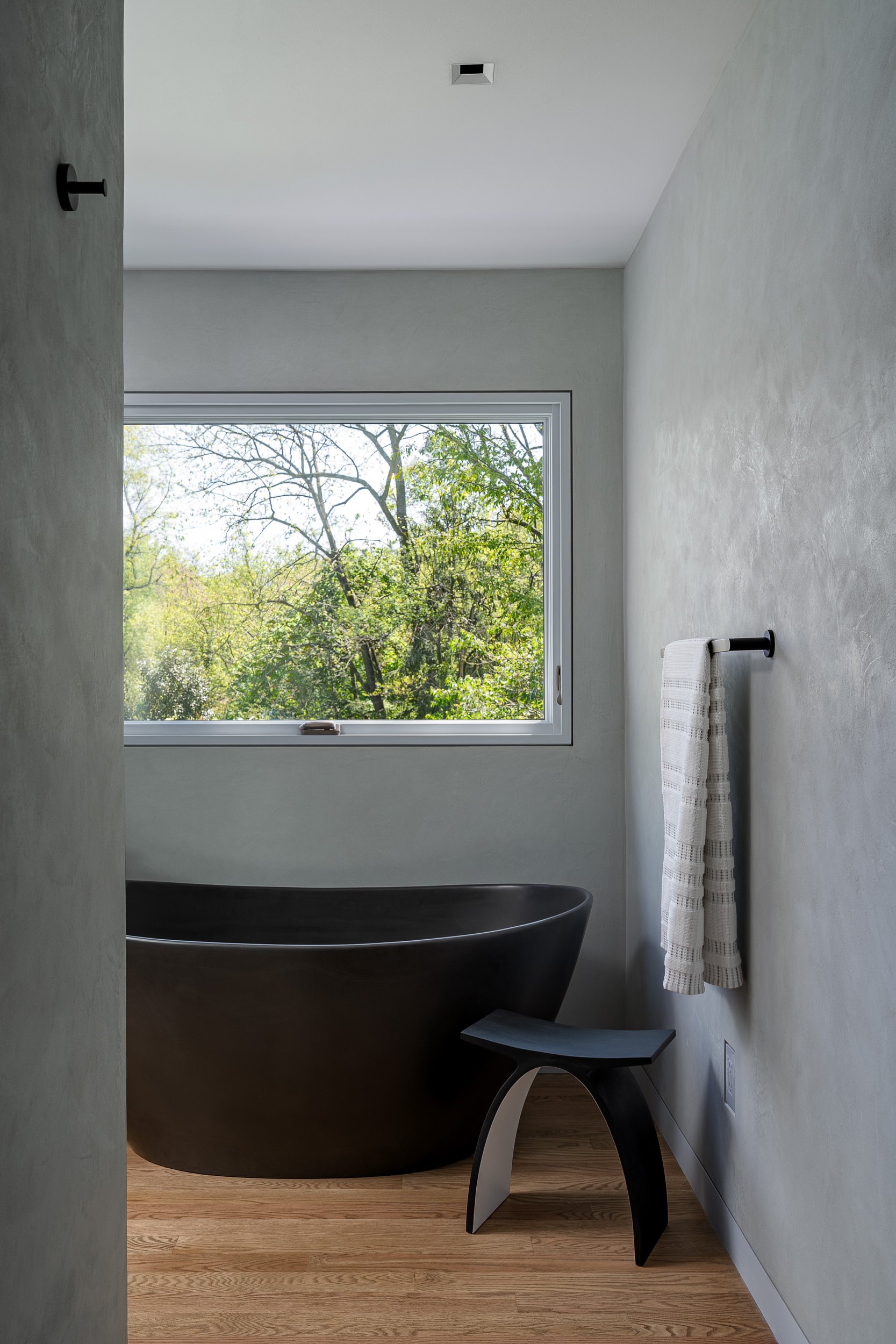 Primary bathroom with a black freestanding tub and Venetian plaster walls, interior design photography in Washington, DC