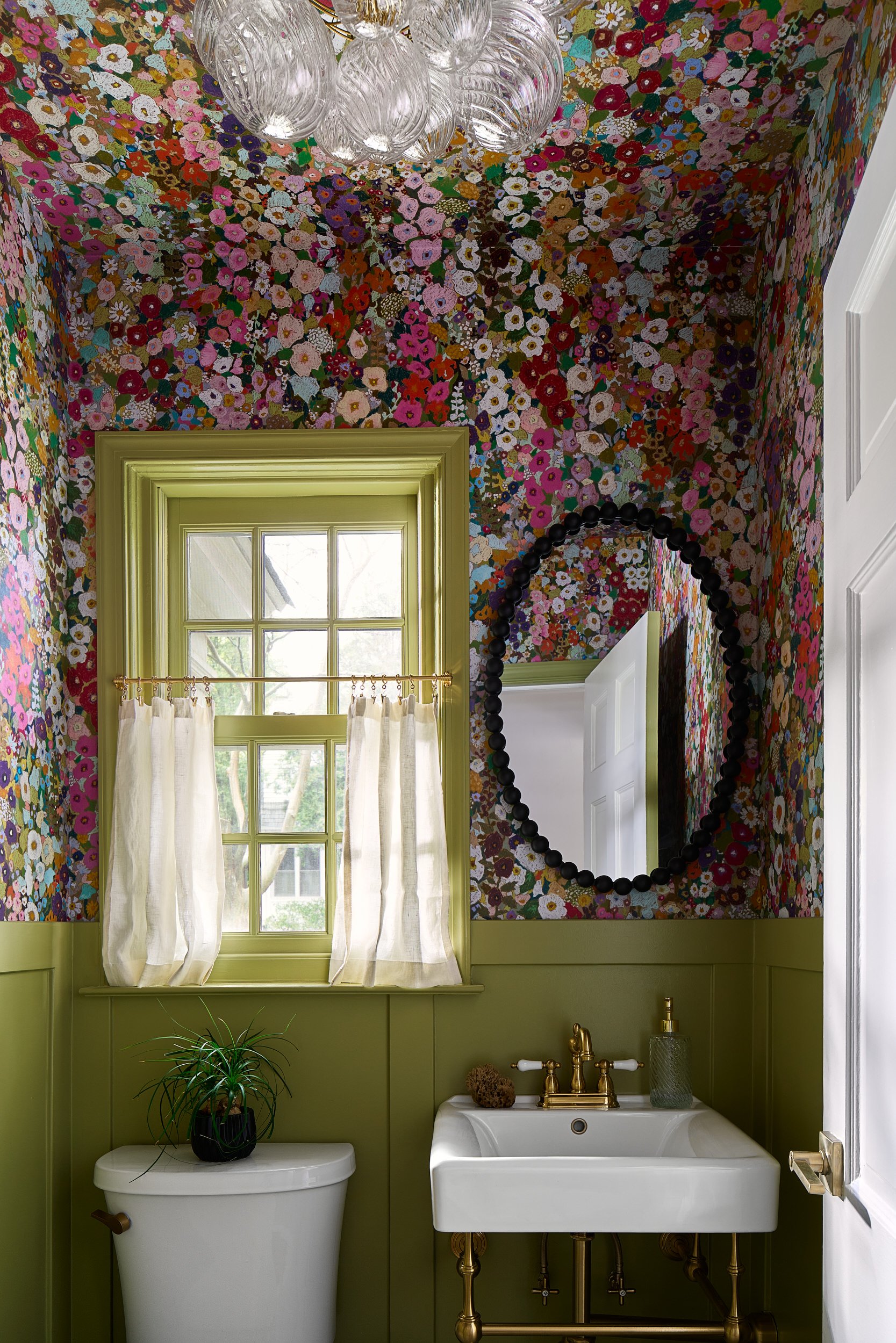 Powder room with floor-to-ceiling floral wallpaper and a black oval mirror, interior design photography in Washington, DC