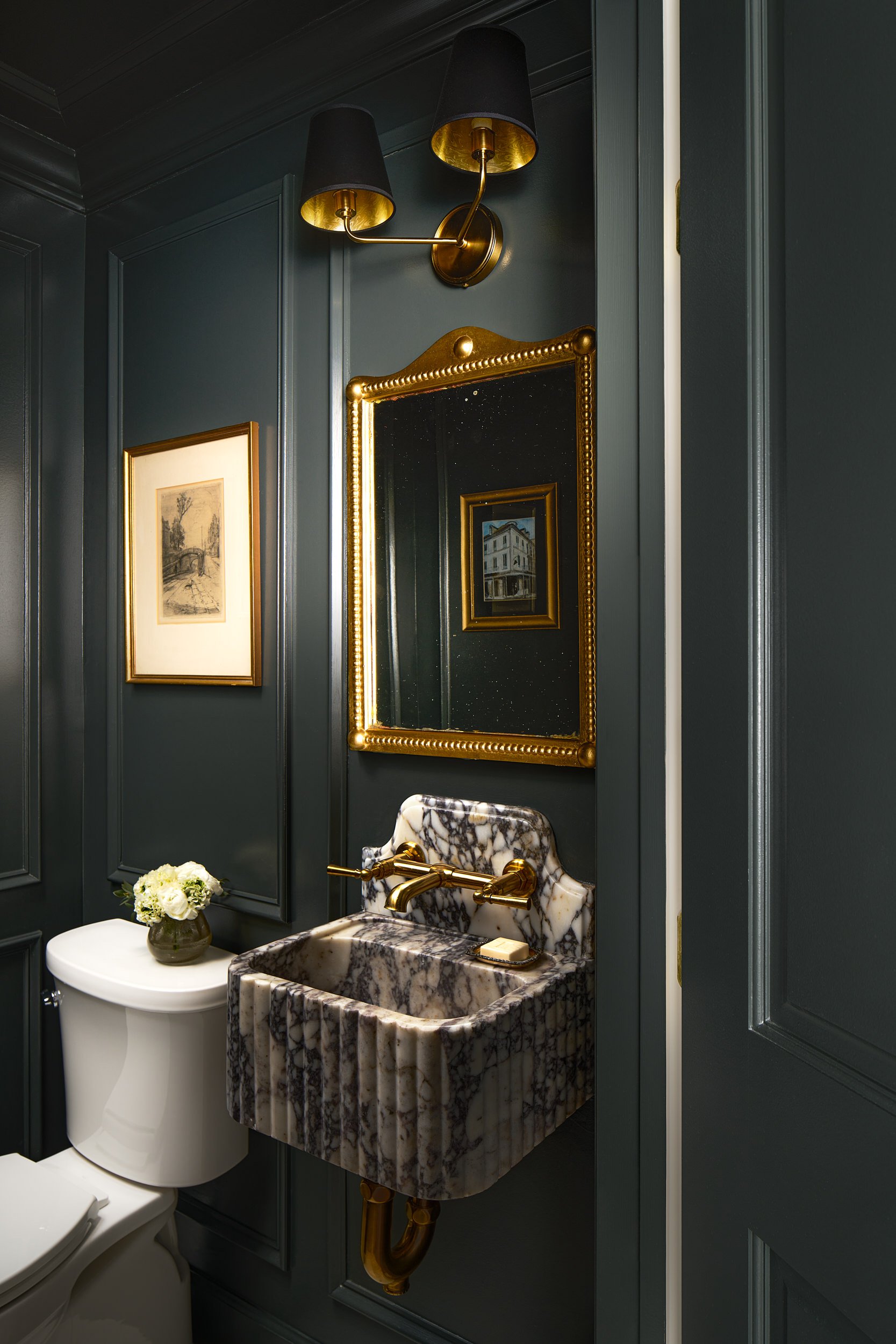 Powder room with dark green walls and a carved marble sink, interior design photography in Northern Virginia