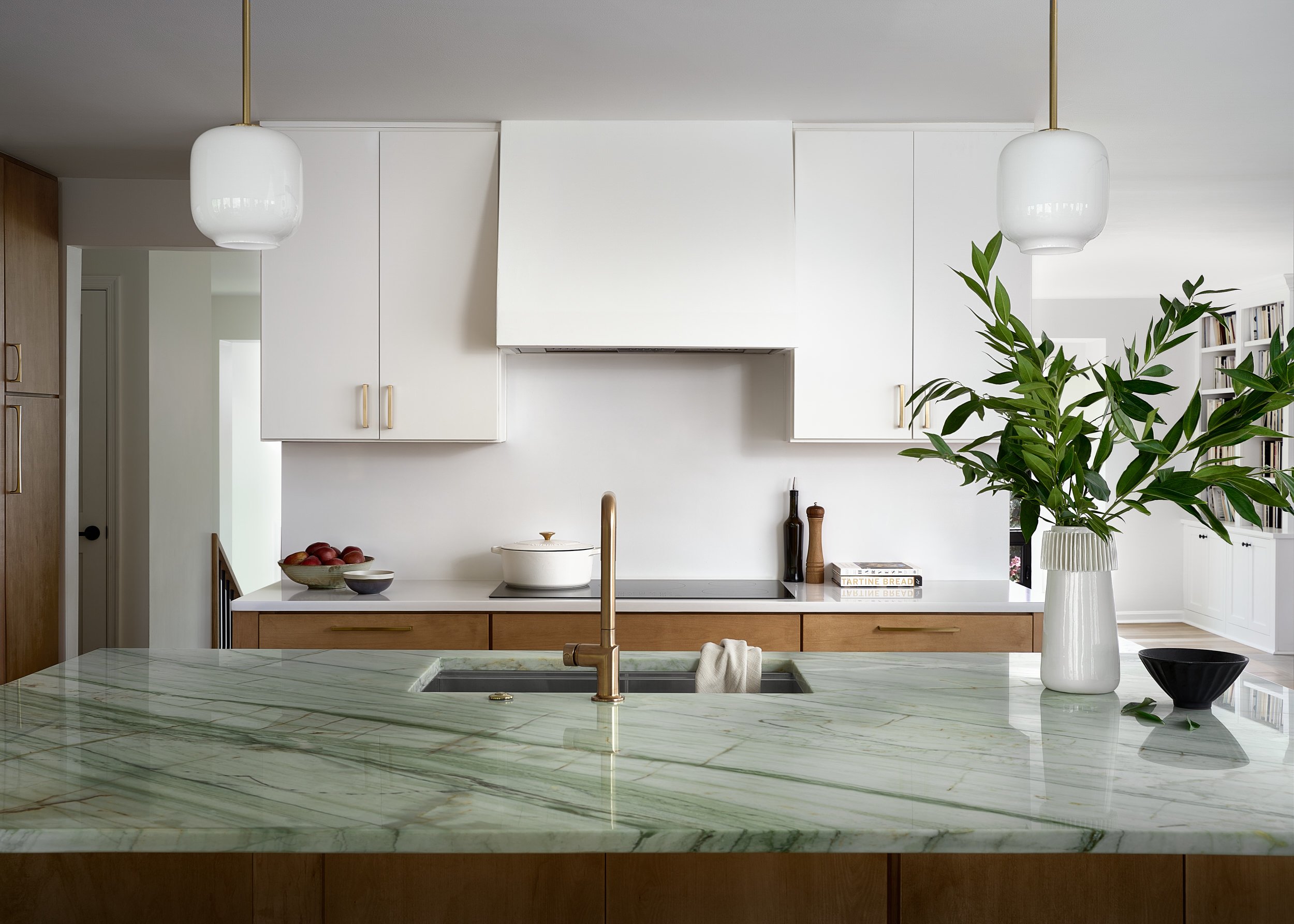 Kitchen with a green marble island, brass faucet, and white cabinetry, interior design photography in Northern Virginia