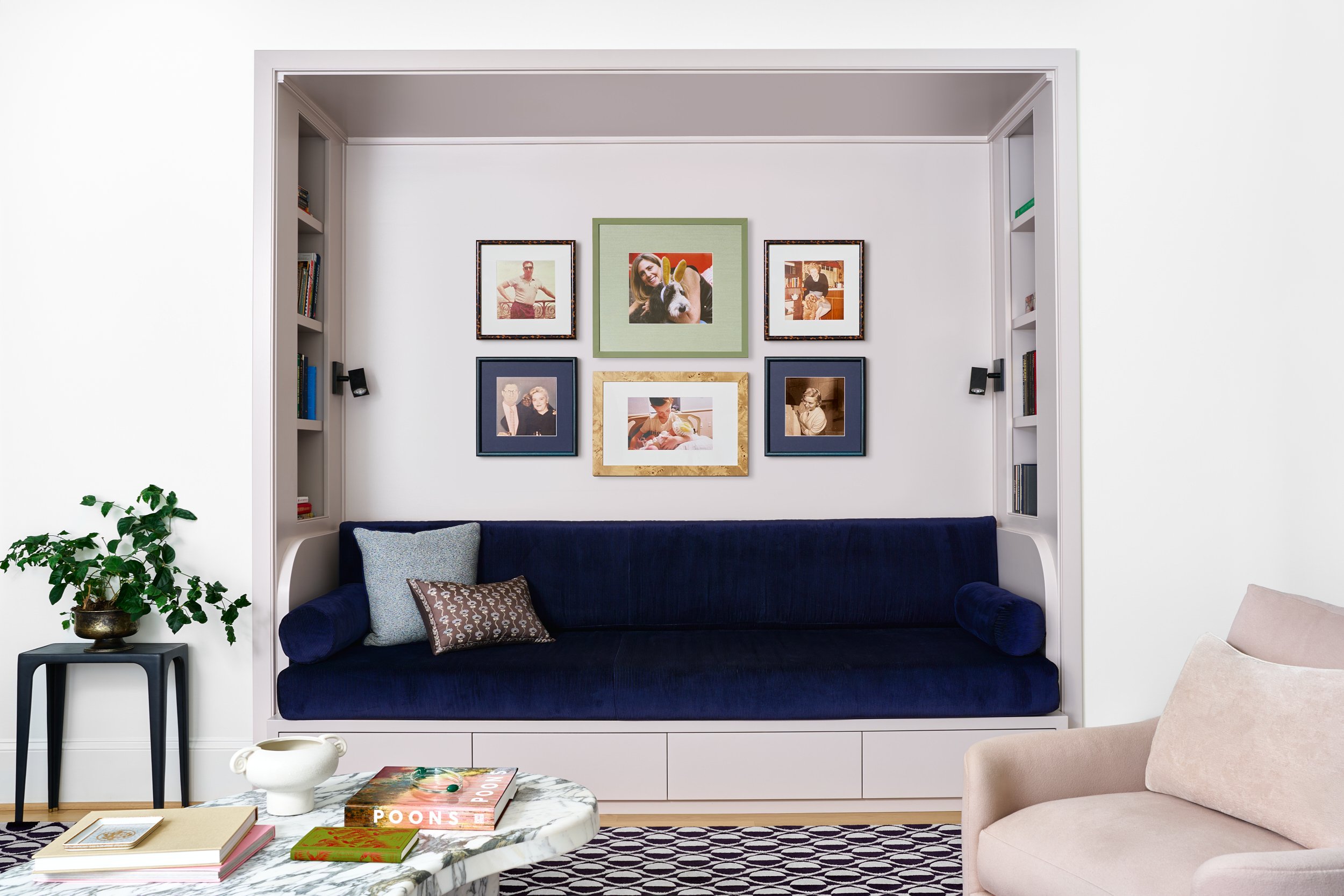 Built-in daybed nook with navy velvet cushions and a gallery wall of framed photos, interior design photography in Maryland
