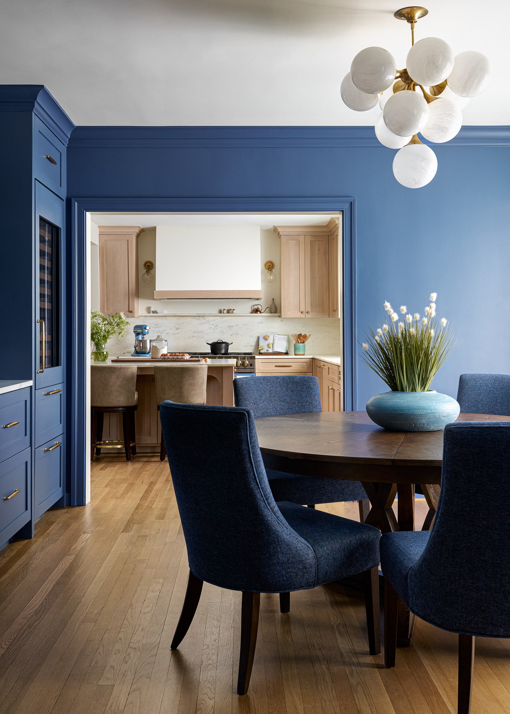 Dining room with navy walls opening to the kitchen, interior design photography in Northern Virginia