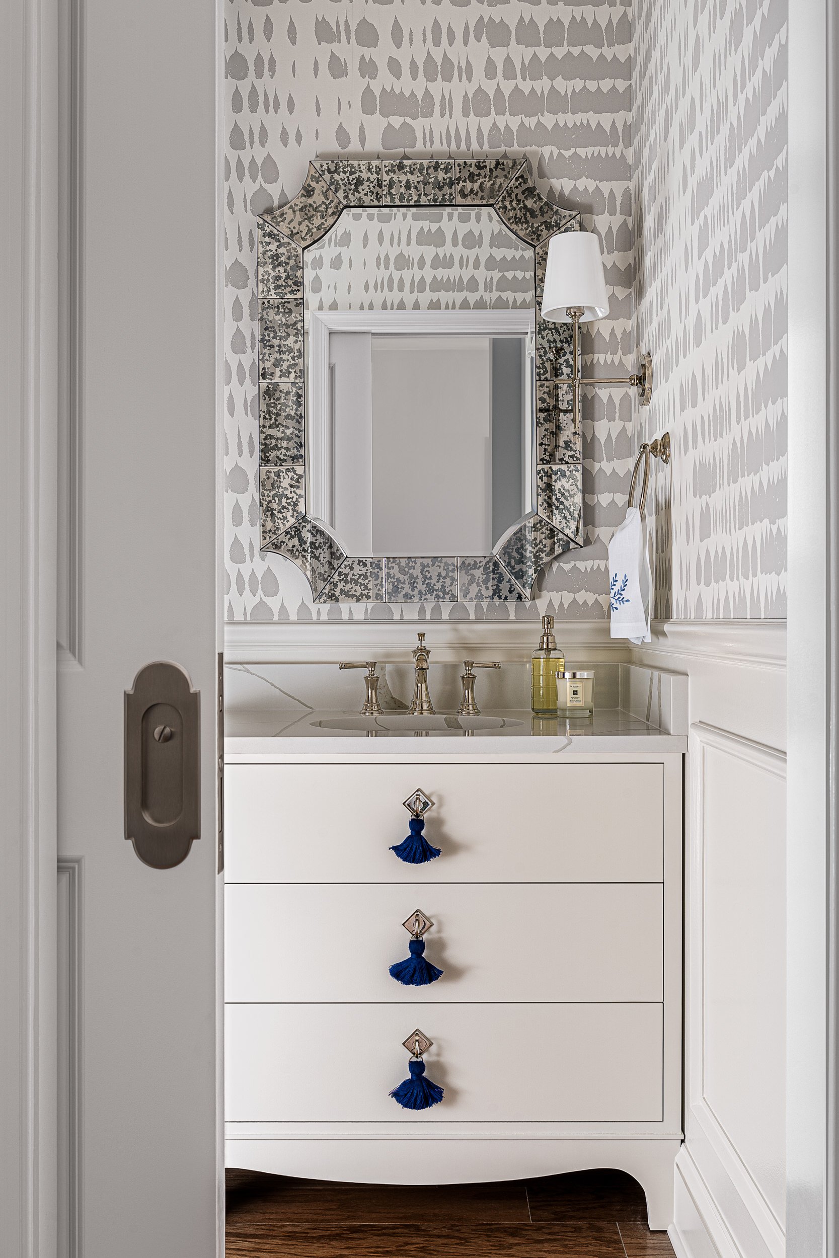 Powder room with gray patterned wallpaper and a pocket door, interior design photography in Northern Virginia