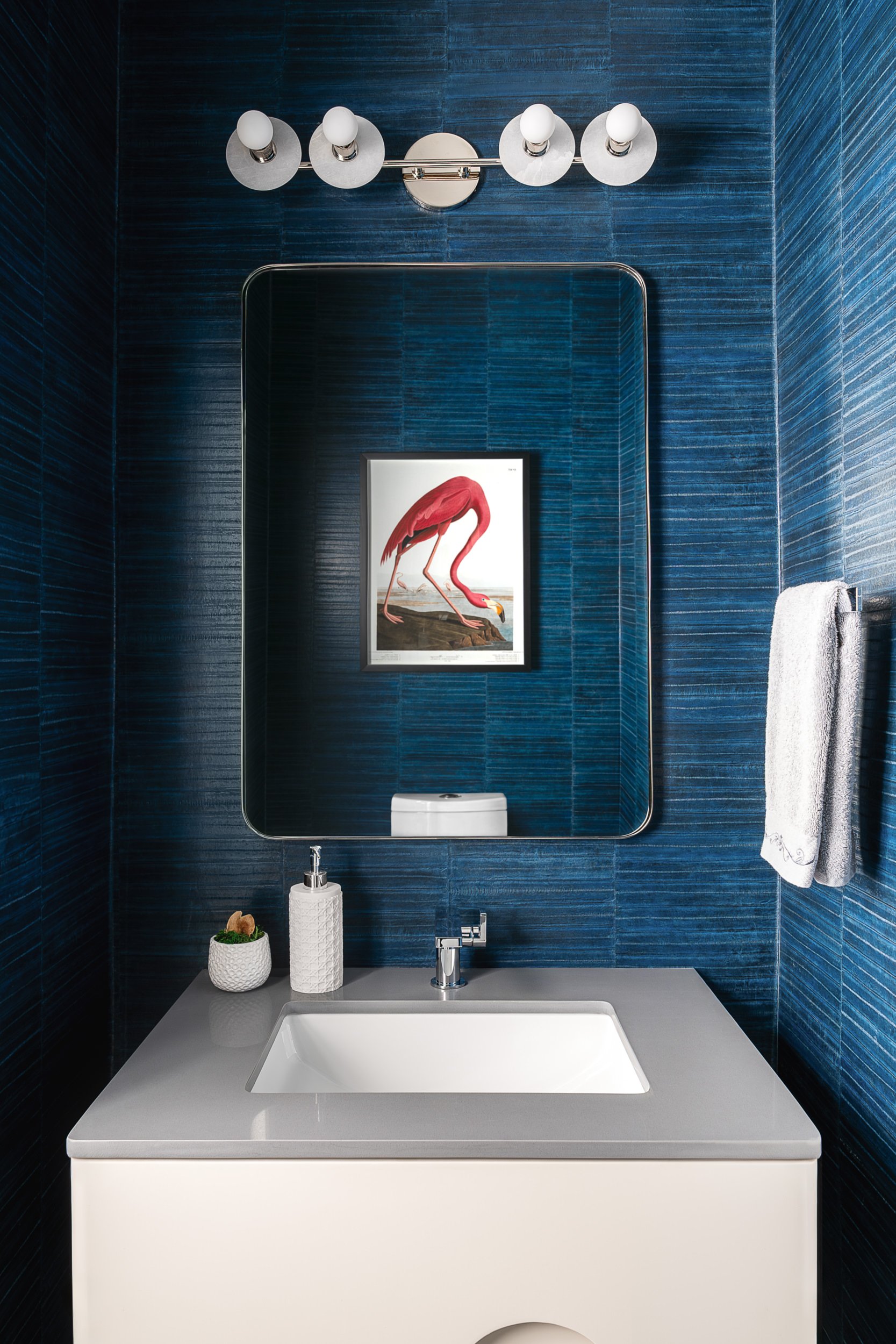 Powder room with navy grasscloth wallpaper and flamingo artwork, interior design photography in Northern Virginia
