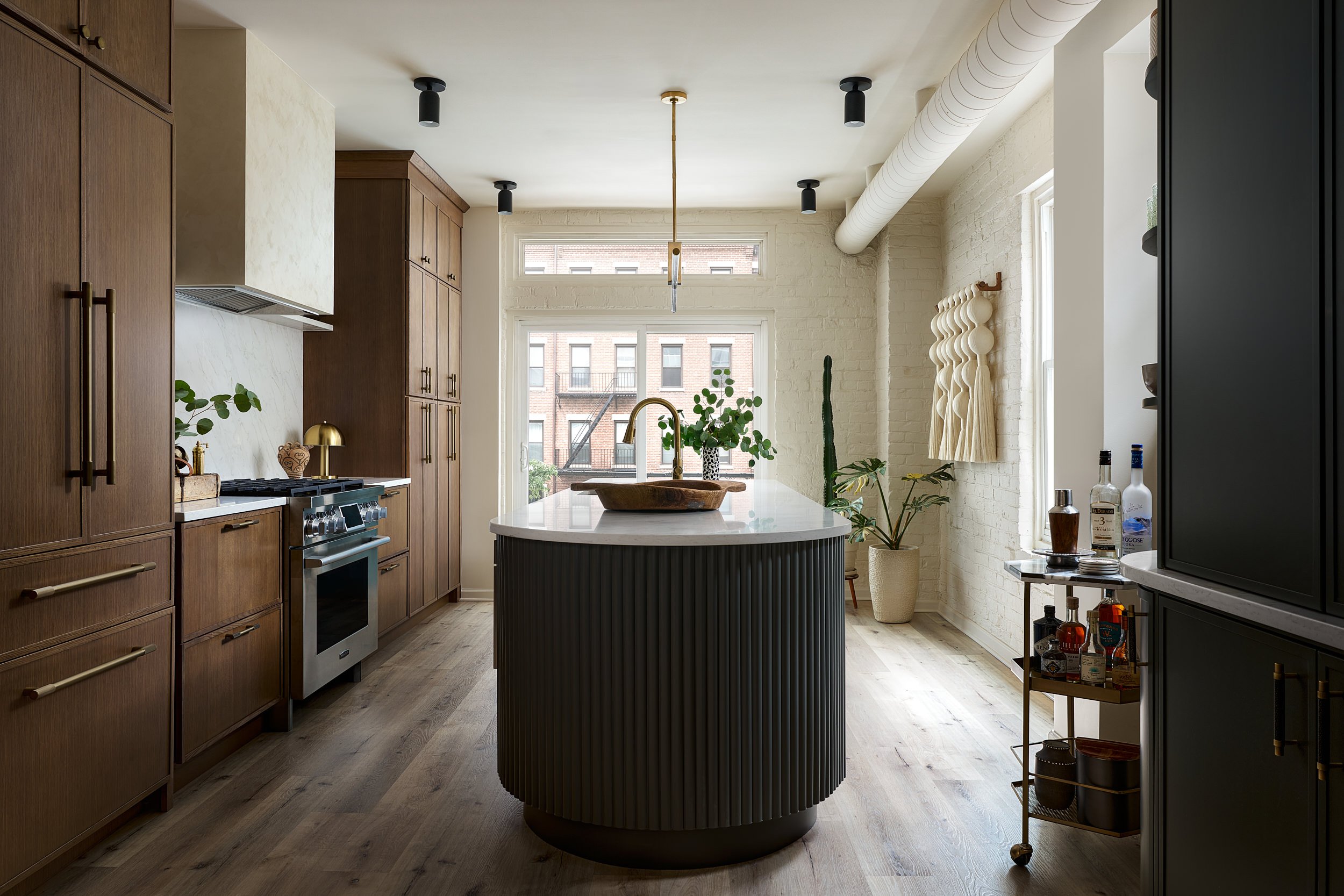 Kitchen with dark wood cabinetry, a round island, and exposed brick wall, interior design photography in Washington, DC