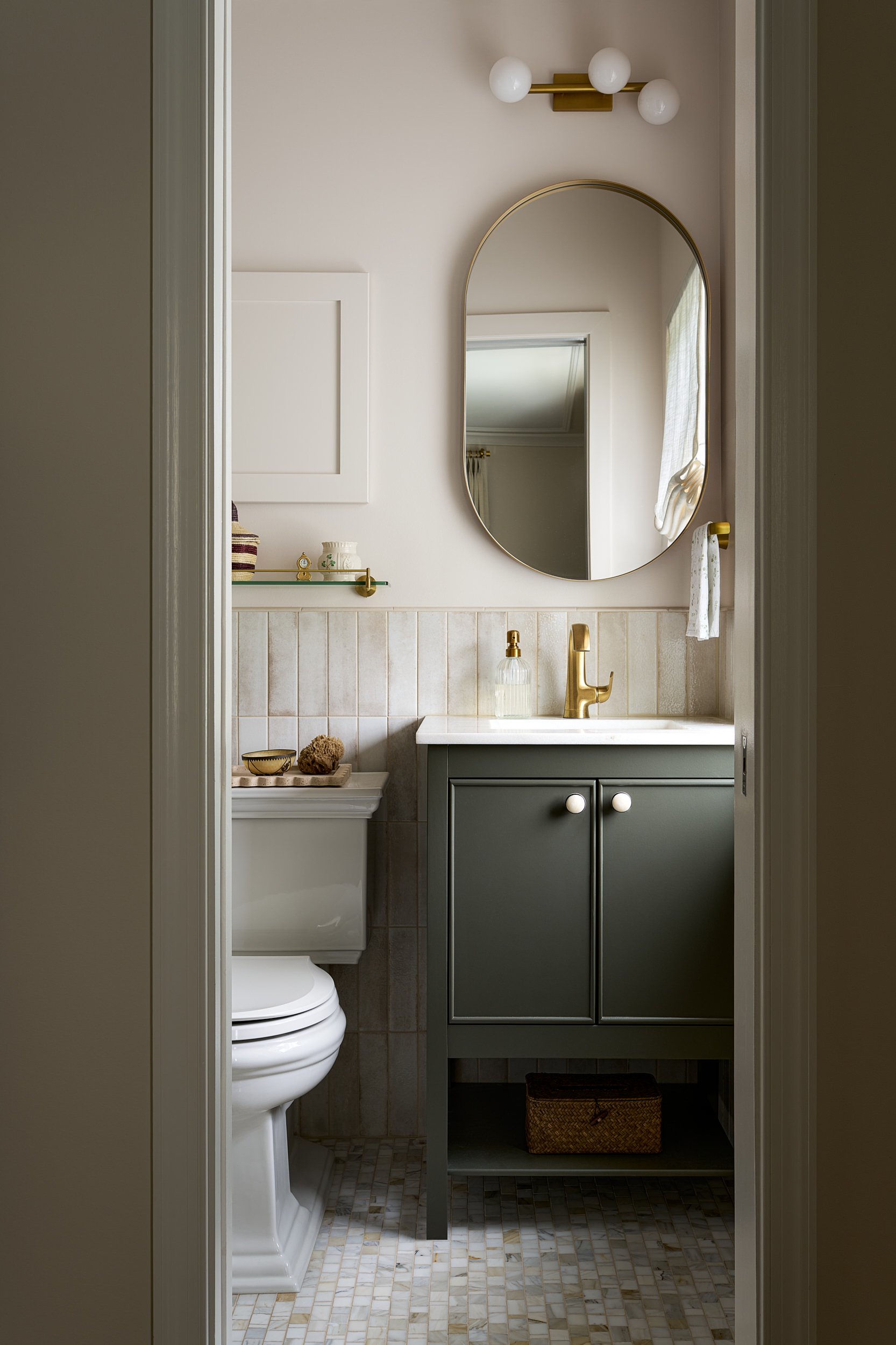 Powder room with a sage green vanity and oval mirror, interior design photography in Washington, DC