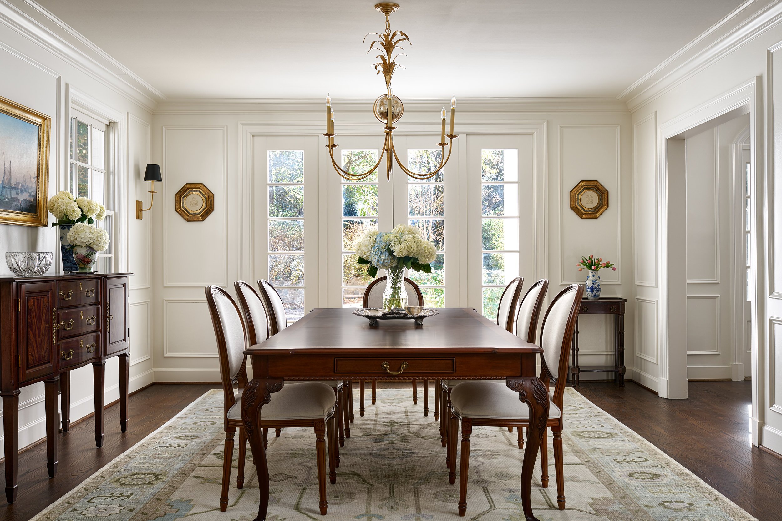 Traditional dining room with paneled walls, French doors, and a gold leaf chandelier, interior design photography in Maryland