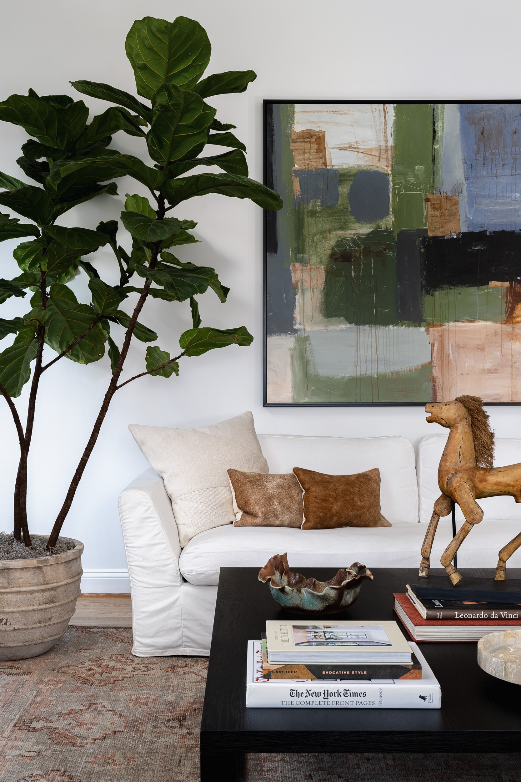Living room with a white slipcovered sofa, fiddle leaf fig tree, and abstract art, interior design photography in the DMV area