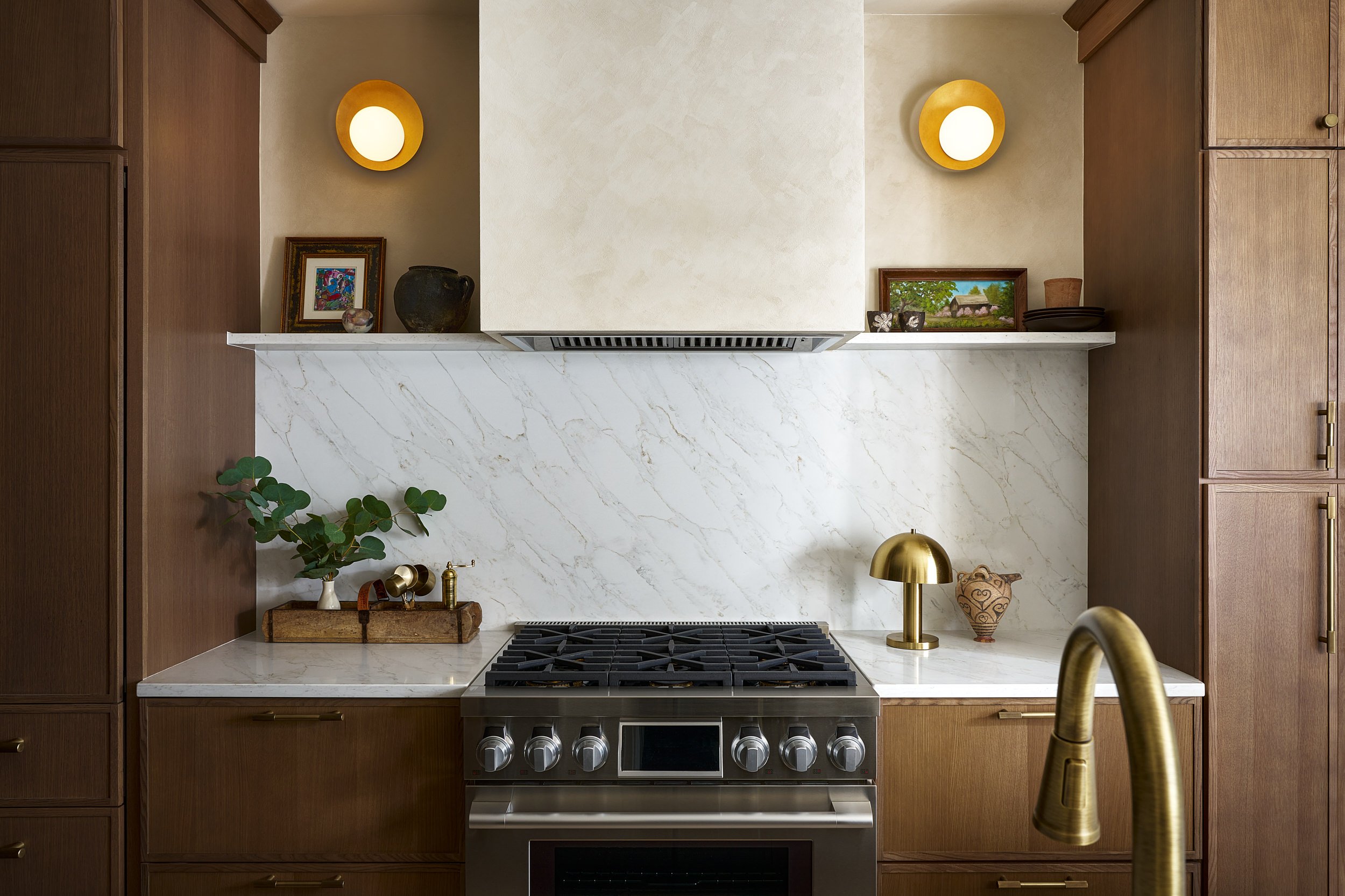 Kitchen range vignette with marble slab backsplash and brass sconces, interior design photography in Northern Virginia