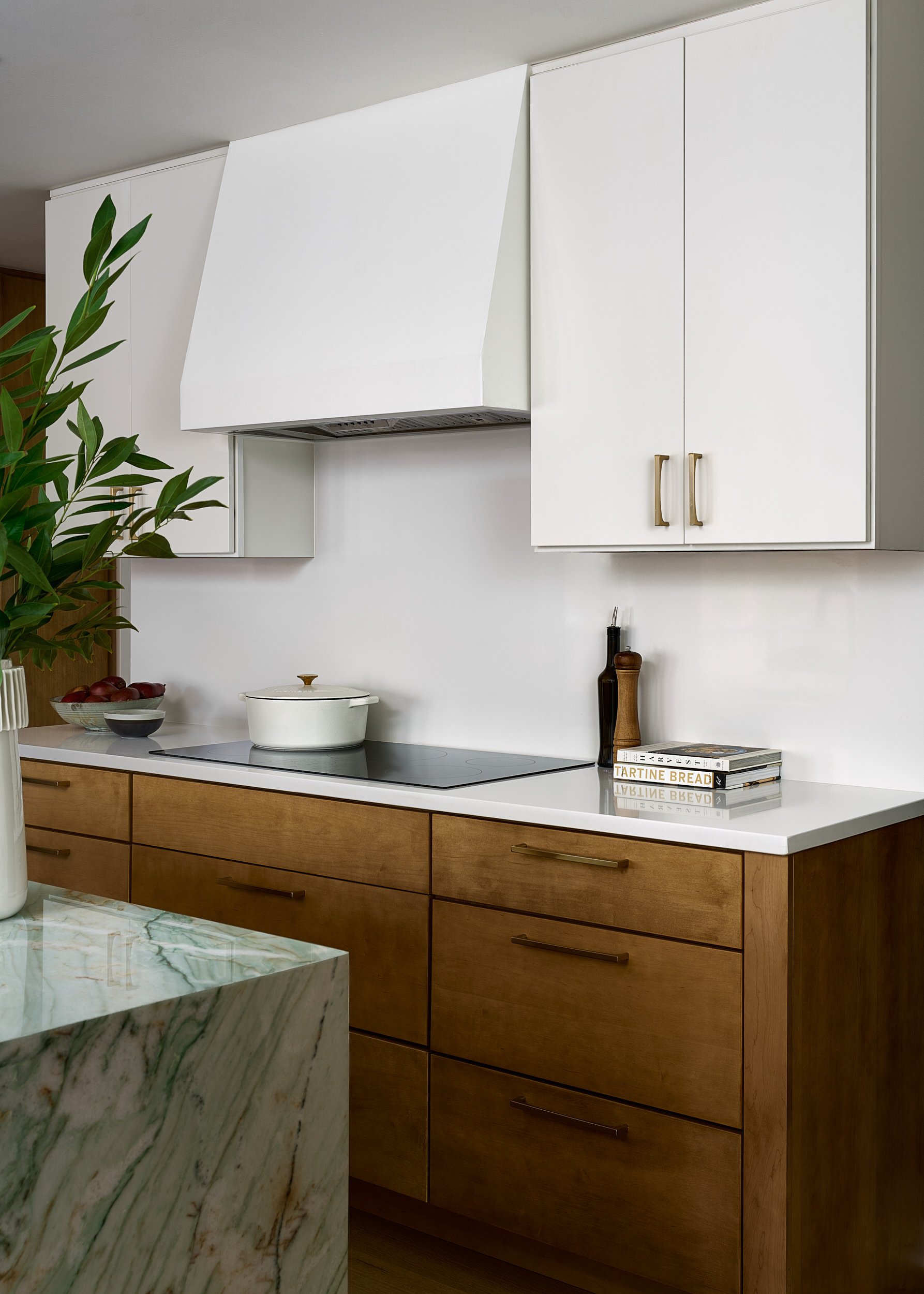 Kitchen with a white range hood, wood cabinetry, and marble island, interior design photography in the DMV area