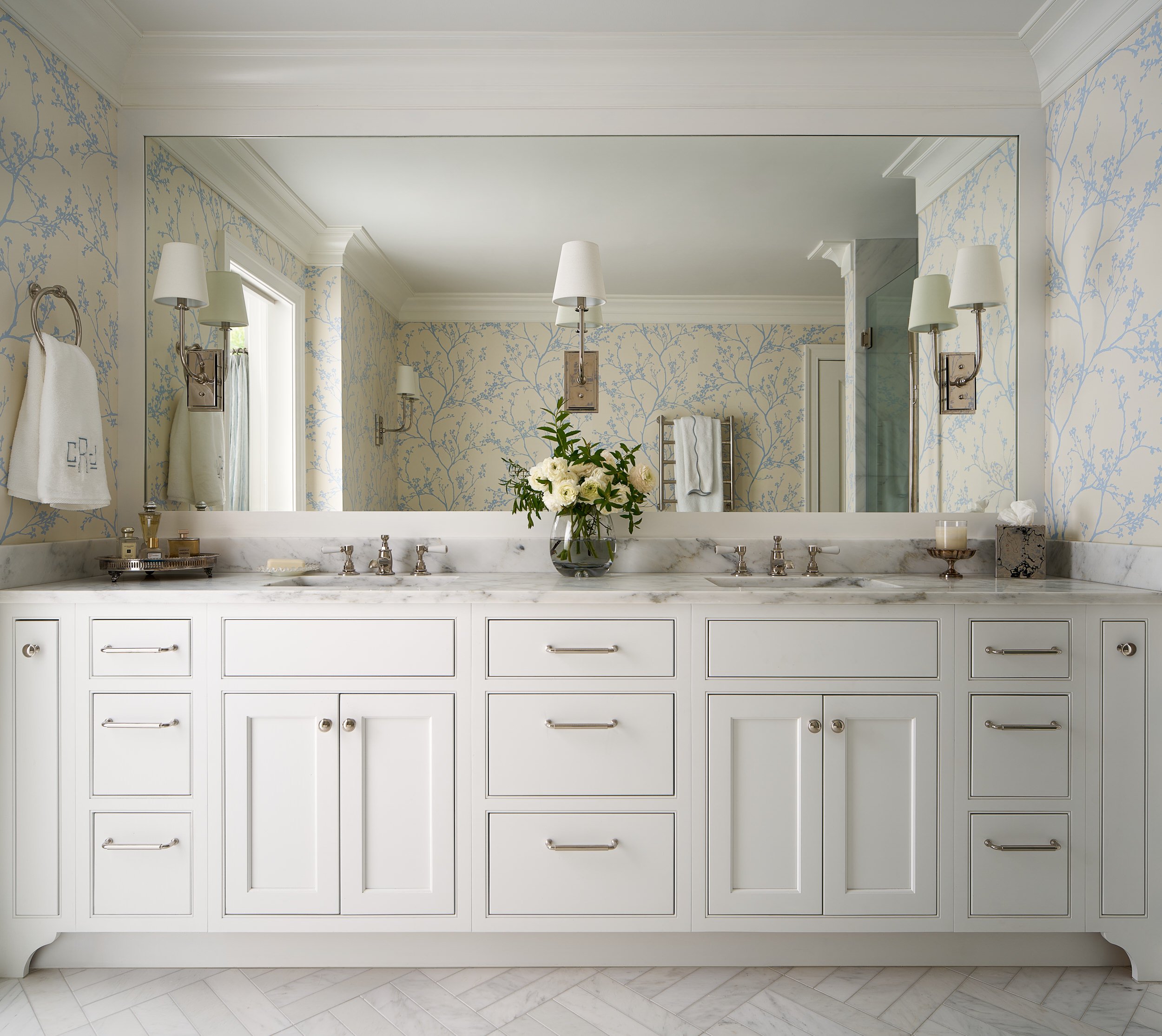 Primary bathroom with a white double vanity, marble counters, and tree branch wallpaper, interior design photography in the DMV area