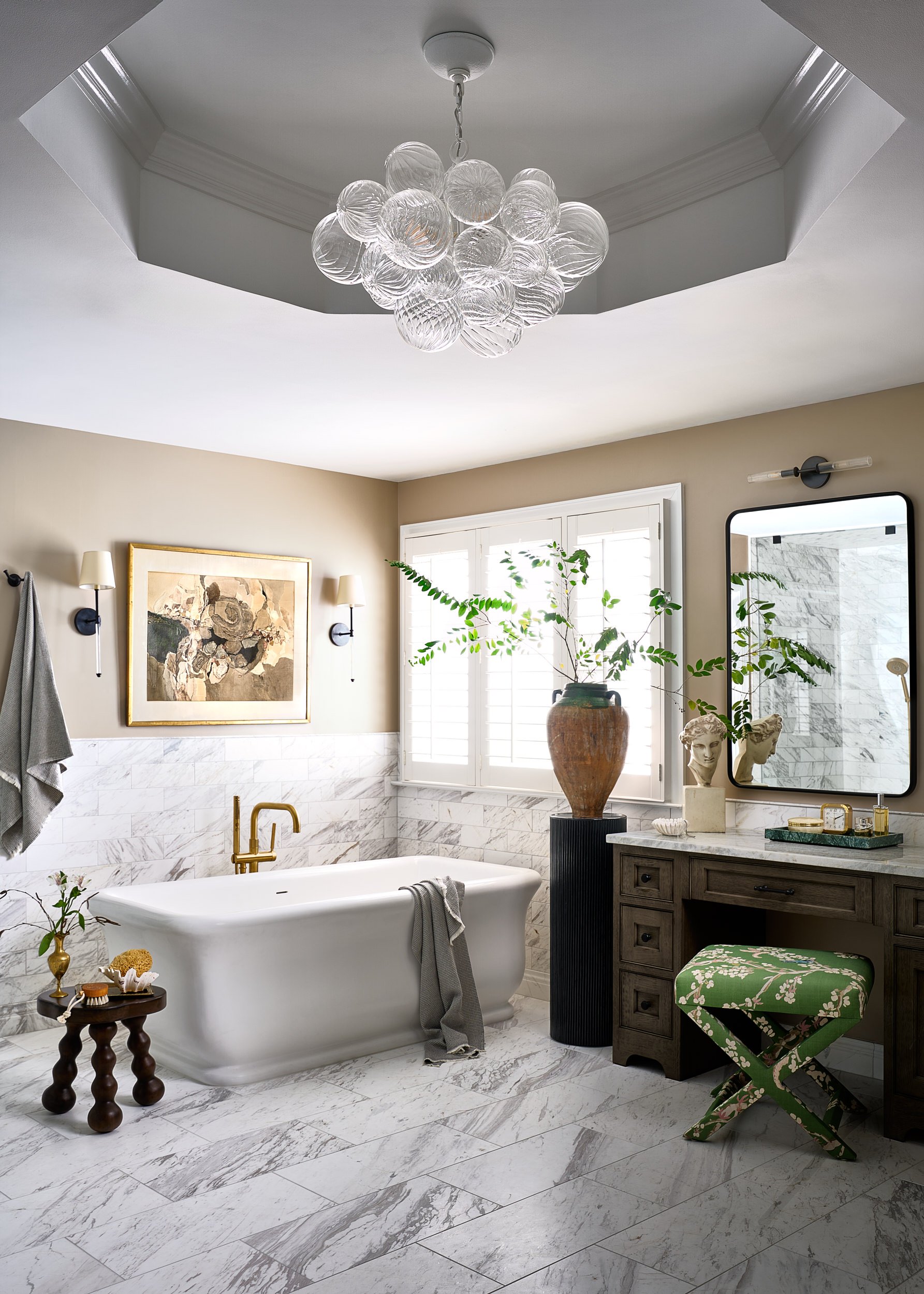 Primary bathroom with a freestanding tub, bubble glass chandelier, and marble tile wainscoting, interior design photography in the DMV area