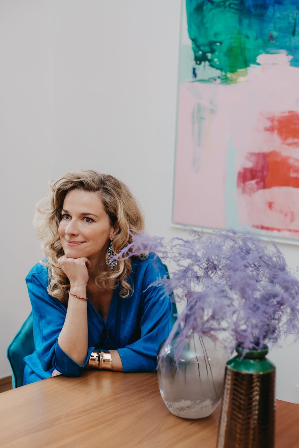 Kristina Sacken im blauen Kleid, nachdenklich am Tisch