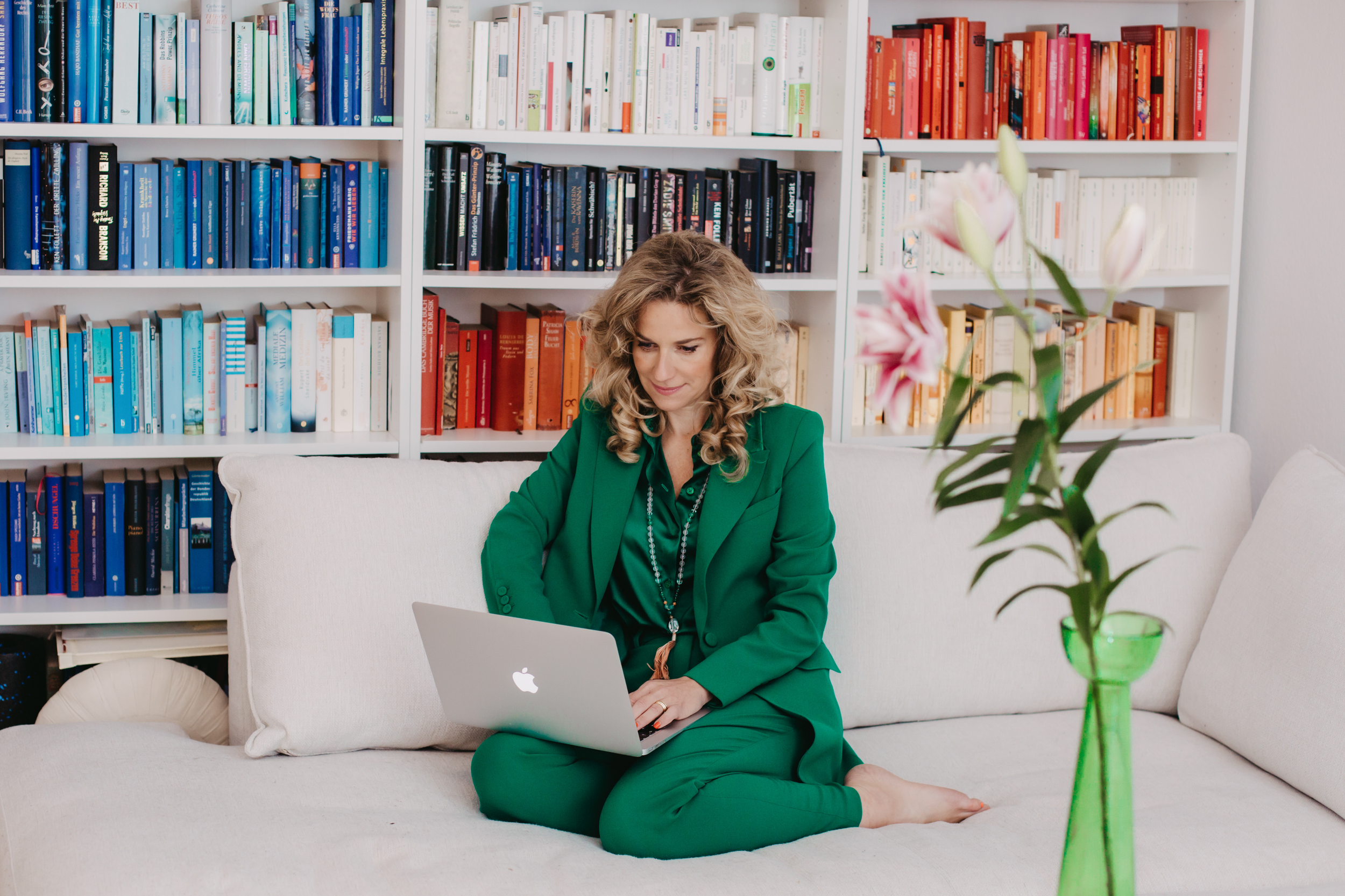 Kristina Sacken im grünen Anzug am Laptop vor einem Bücherregal