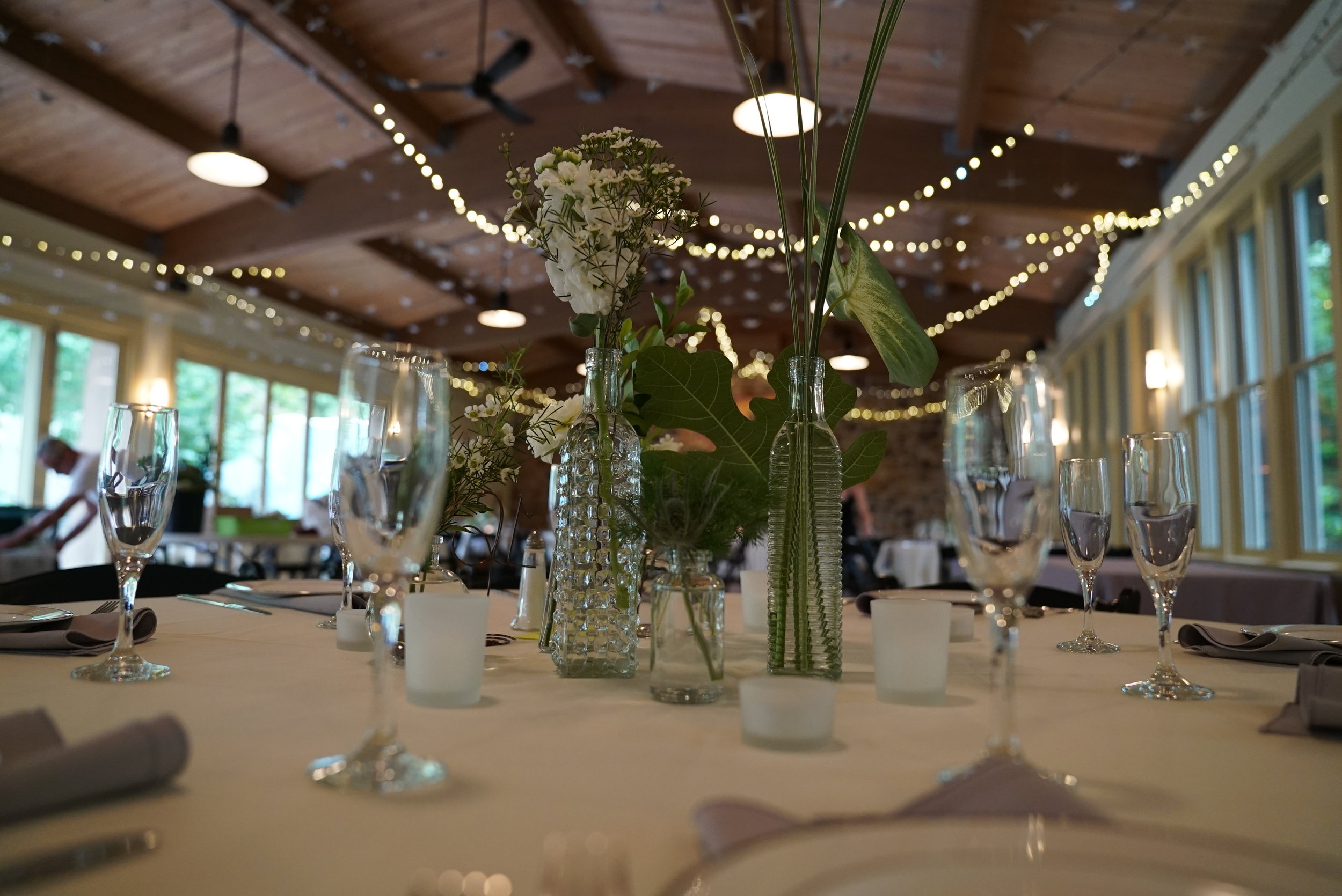  I used upwards of 8 different bottle shapes to create a eclectic yet cohesive centerpiece. We wanted people to be able to see each other over the flowers, as all the tables were round.&nbsp; 