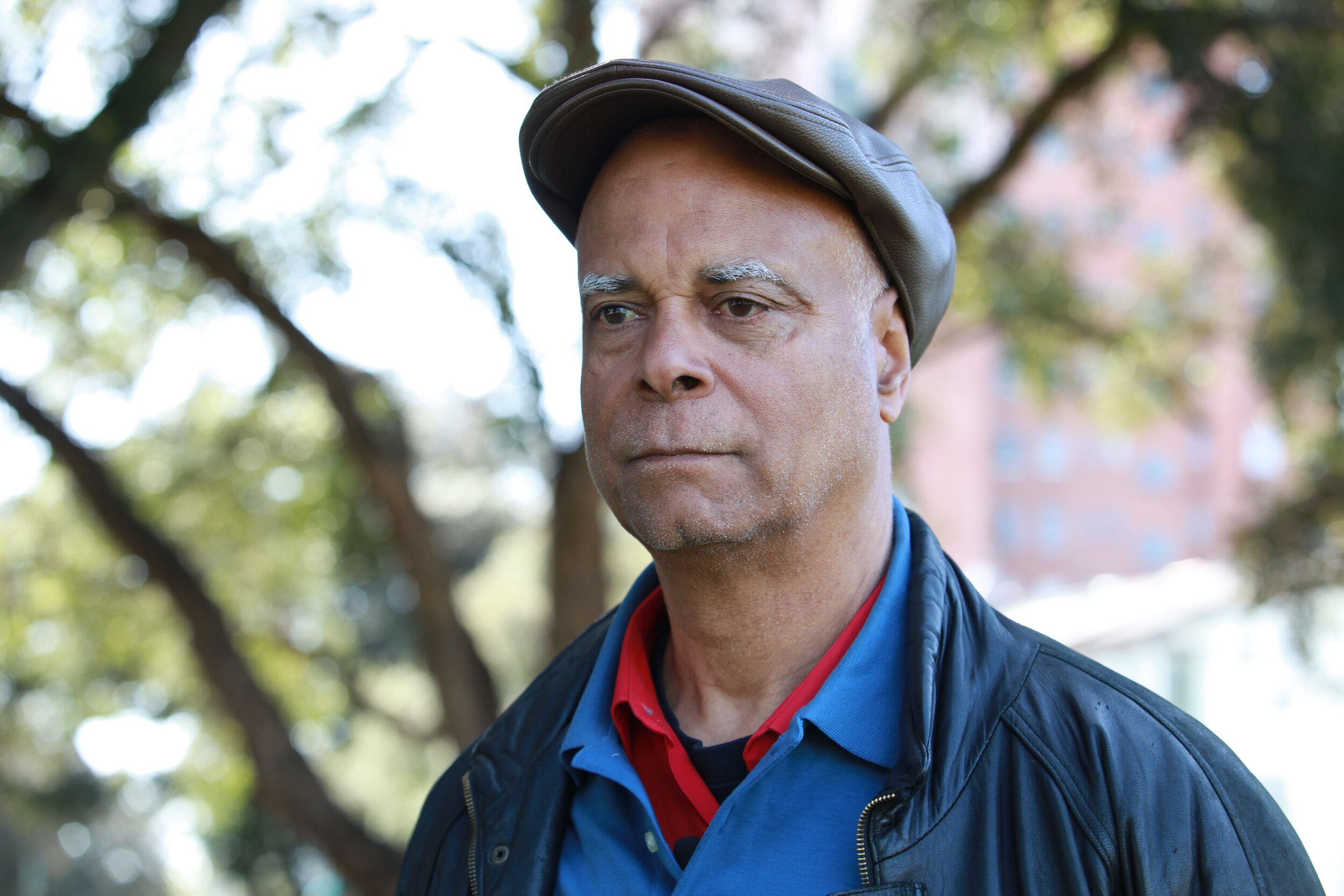 Charles Curtis Blackwell stands and stares just off to the side of the camera. He is wearing layers and a hat. He has a thoughtful expression on his face.