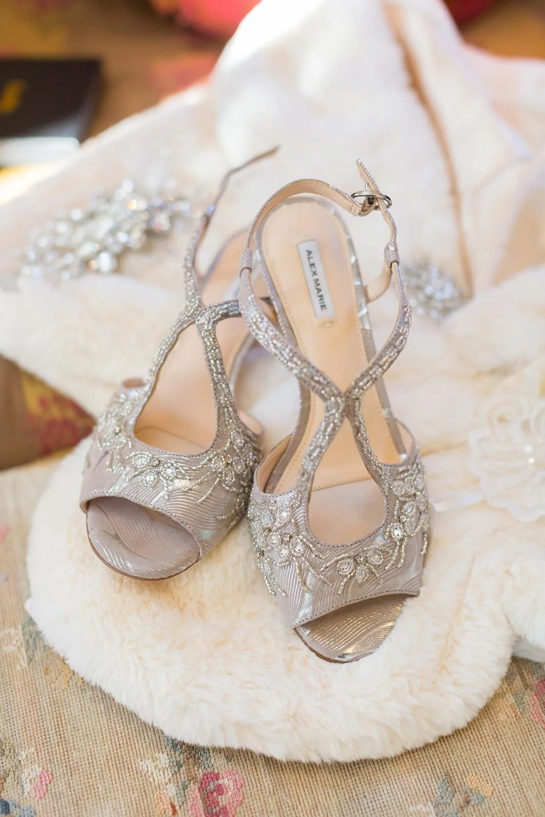 Silver bridal heels styled on a white fur wrap for wedding details.