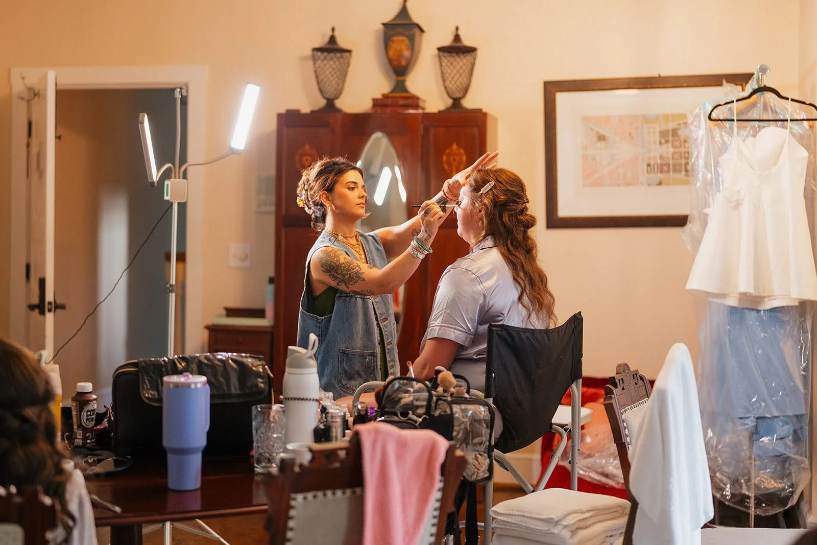 Bride getting her makeup done in an estate bridal suite with her wedding dress hanging nearby.