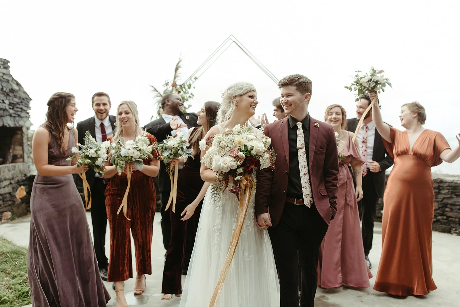 Bride and groom walking with their wedding party after the ceremony, smiling and celebrating.
