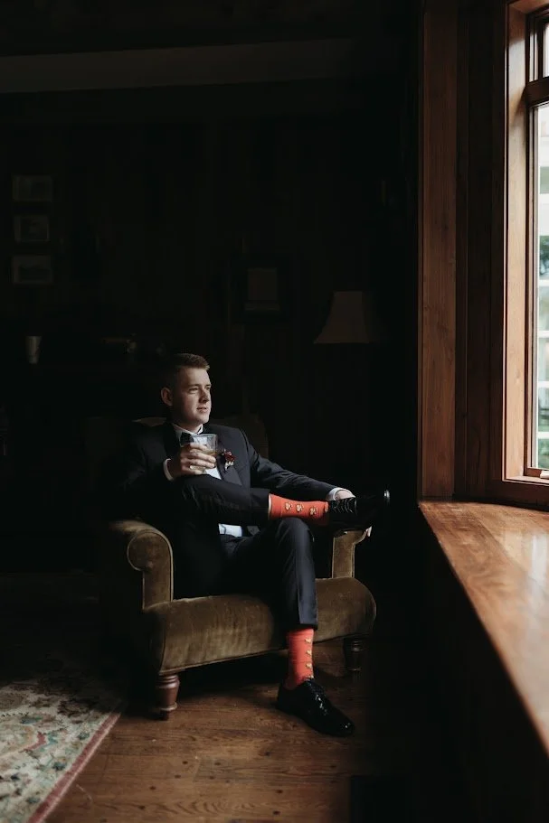 Bride in a wedding gown and veil holding a large bouquet of white and blush roses in soft natural light
