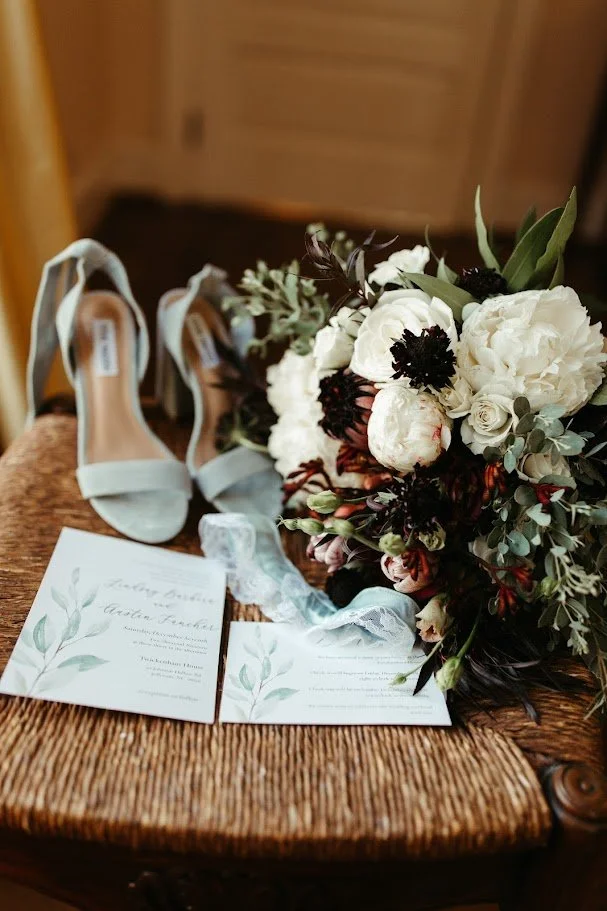 Handwritten wedding vow books photographed with soft floral details before the ceremony.